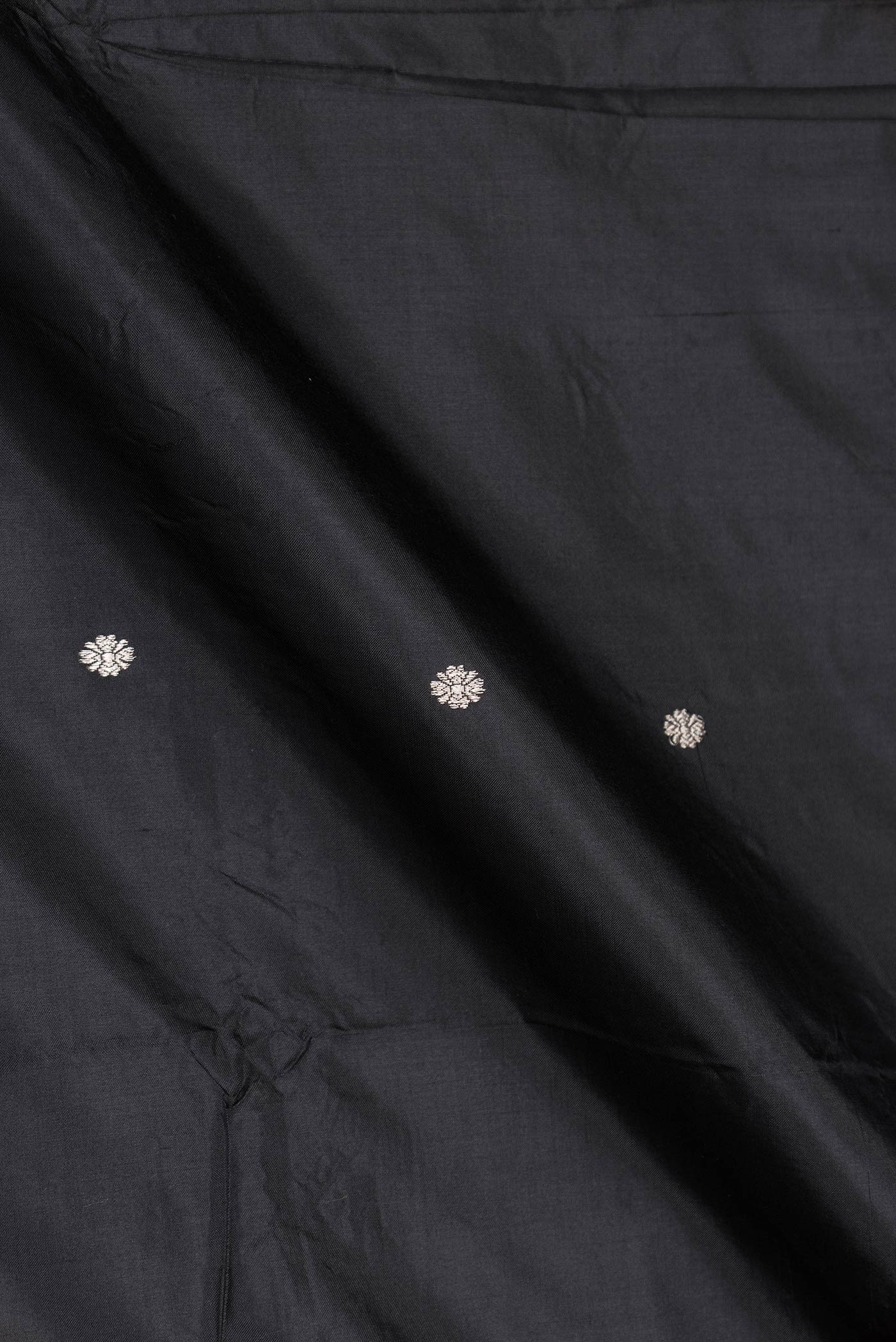 Close up of Black Dual Tone Banarasi Silk Saree with Zari Butta on the body and Zari Border displaying folds