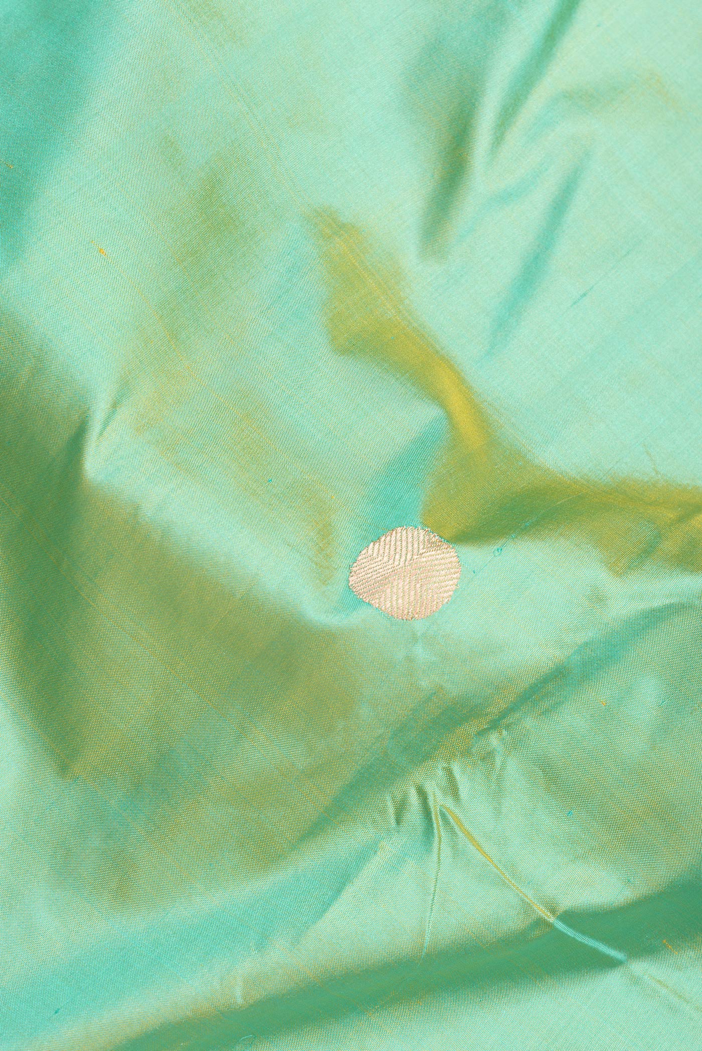 Close up of Green Dual Tone Banarasi Silk Saree with Zari Butta on the body and Paithani Border.  displaying folds