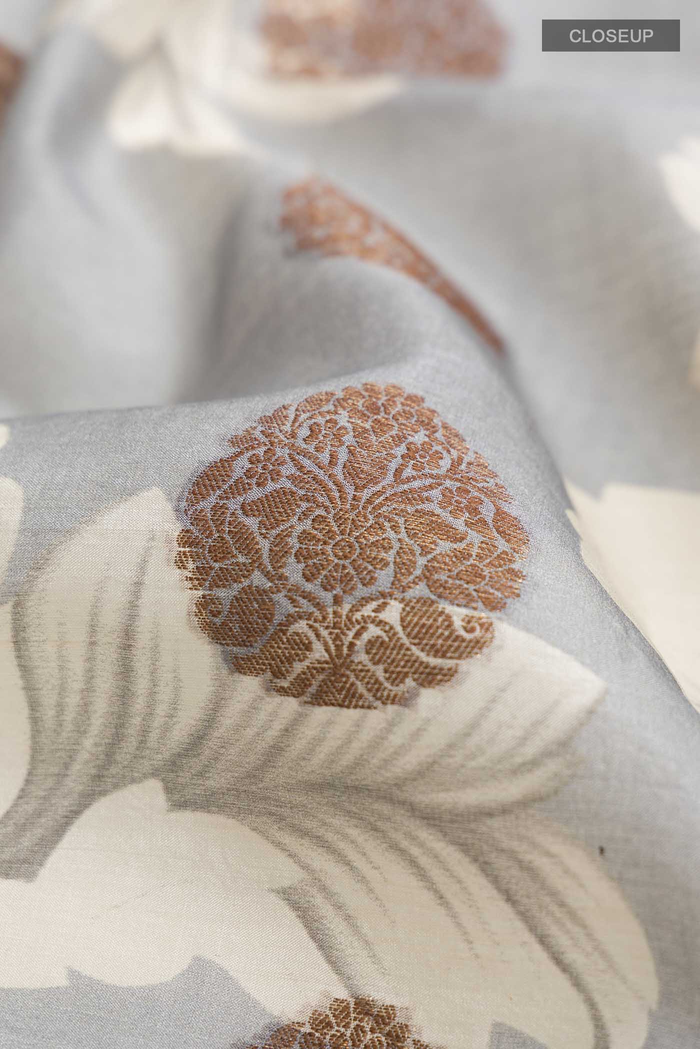 Close up of Grey Tussar Silk Saree with Zari Butta on the body and Zari Border displaying folds
