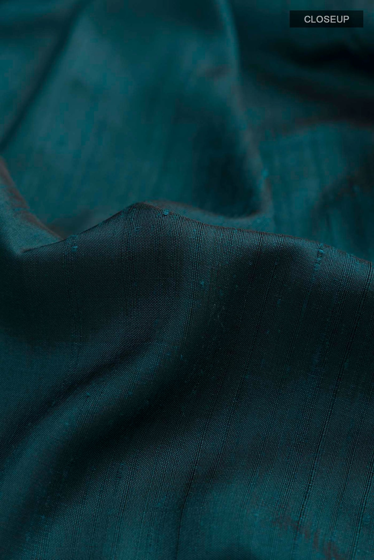 Close up of Teal Soft Silk Saree with Plain Body and Printed Border displaying folds