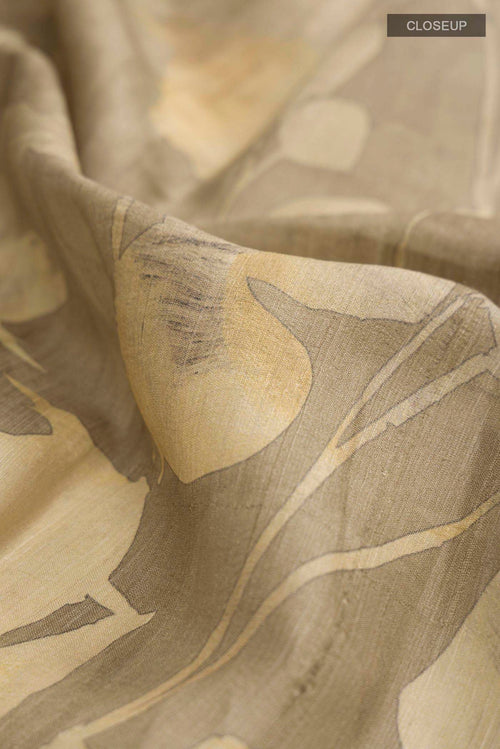 Close up of Beige Tussar Silk Saree with Printed design on the body and Zari Border displaying folds