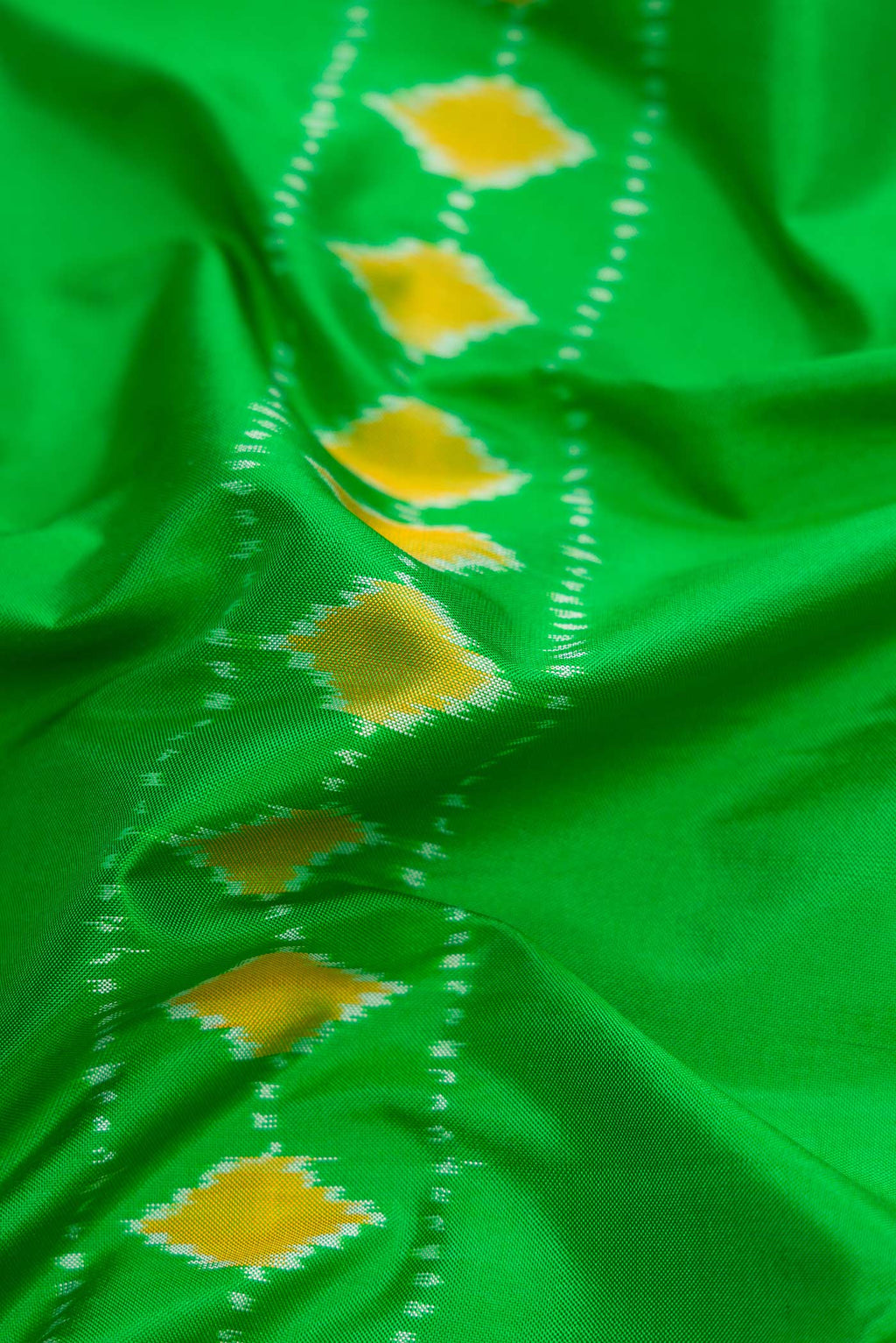 Close up of Parrot Green Dual Tone Rajkot Patola Silk Saree with Ikat Print on the body and Ikat Border displaying folds