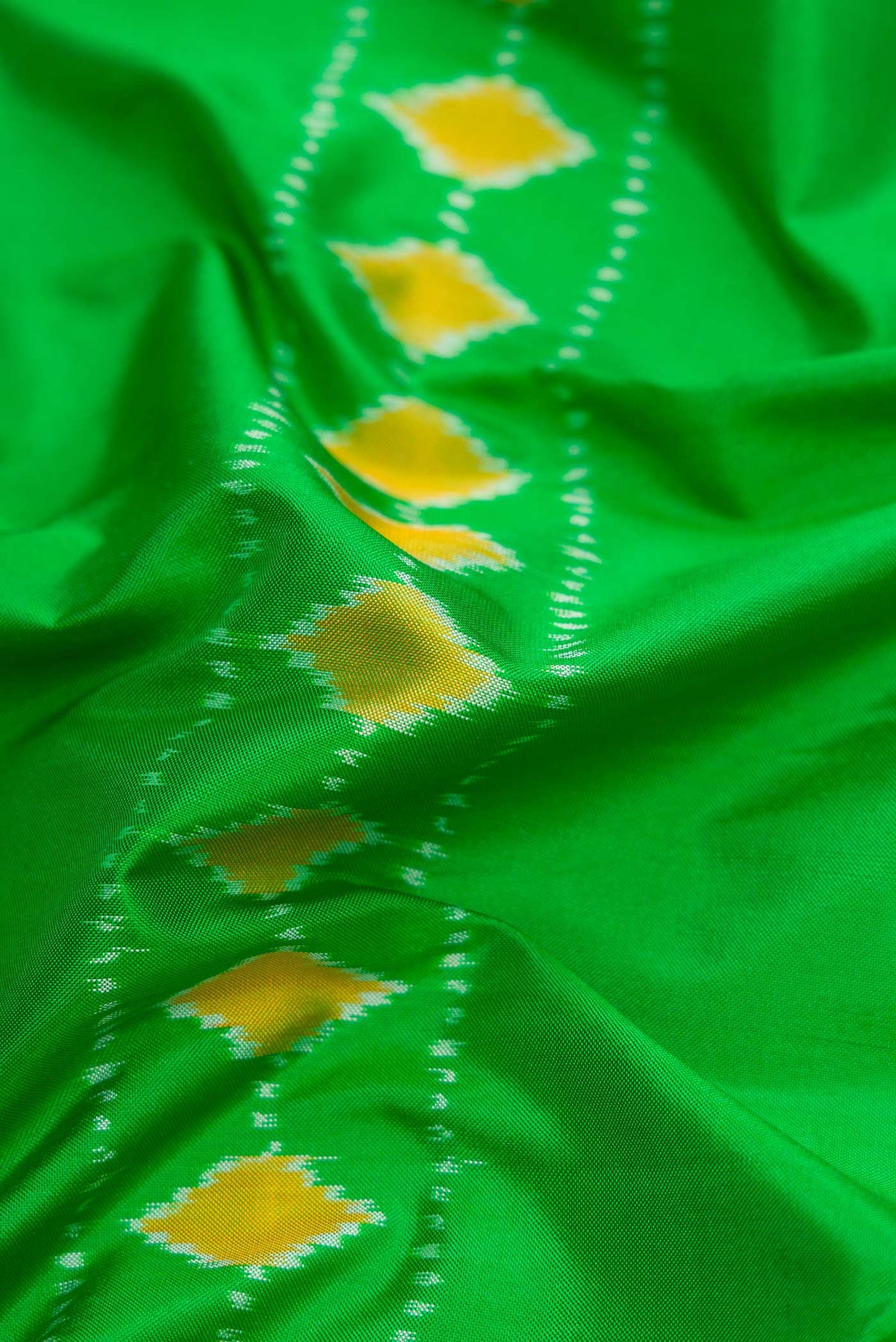 Close up of Parrot Green Dual Tone Rajkot Patola Silk Saree with Ikat Print on the body and Ikat Border displaying folds