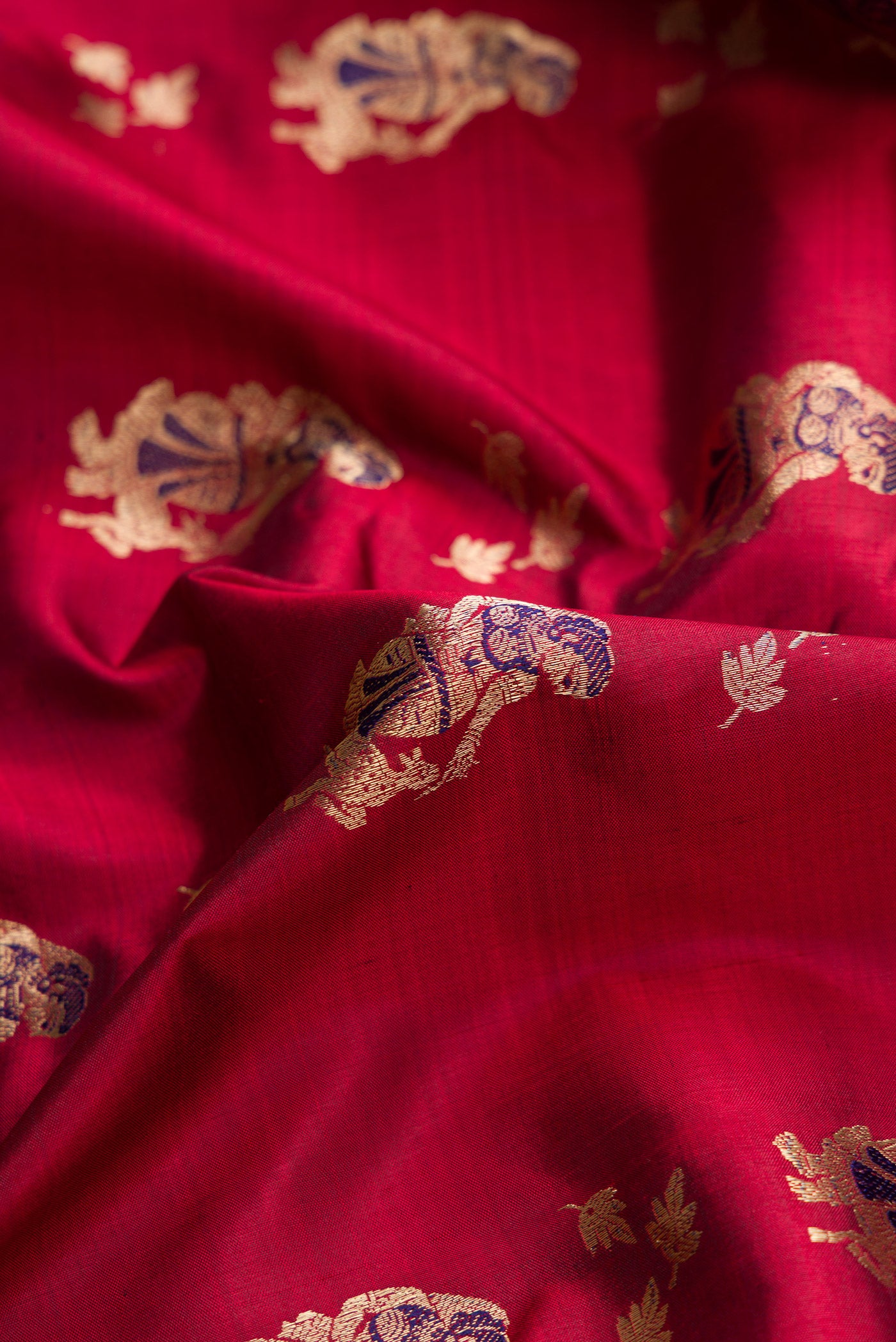 Close up of Maroon Dual Tone Baluchari Silk Saree with Zari And Thread Butta on the body and Fancy Border.  displaying folds