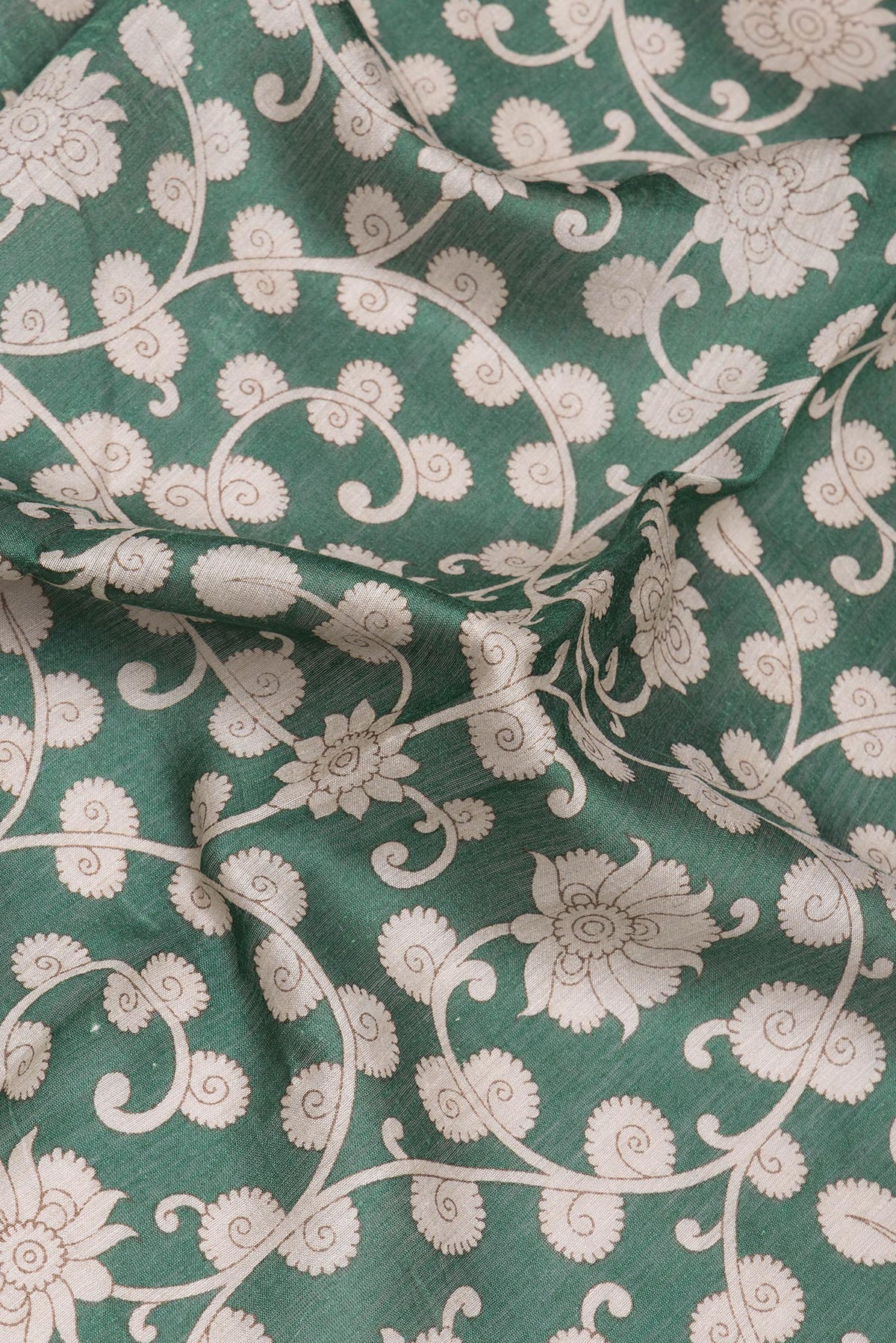Close up of Green Tussar Silk Saree with Printed design on the body and Zari Border.  displaying folds