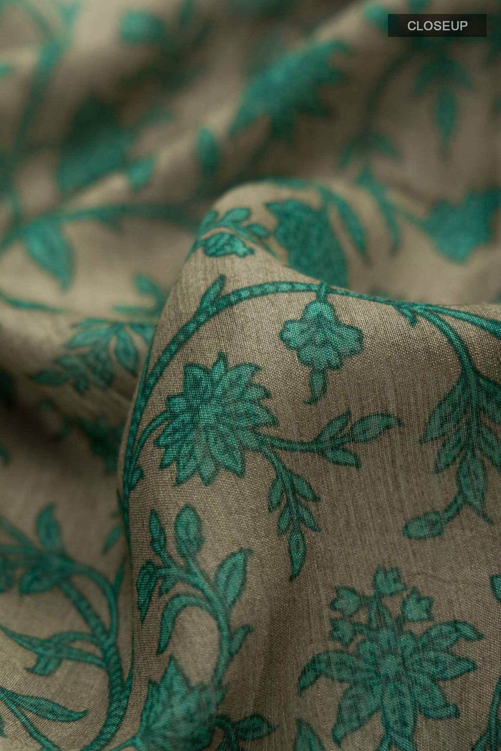 Close up of Green Tussar Silk Saree with Printed design on the body and Zari Border displaying folds