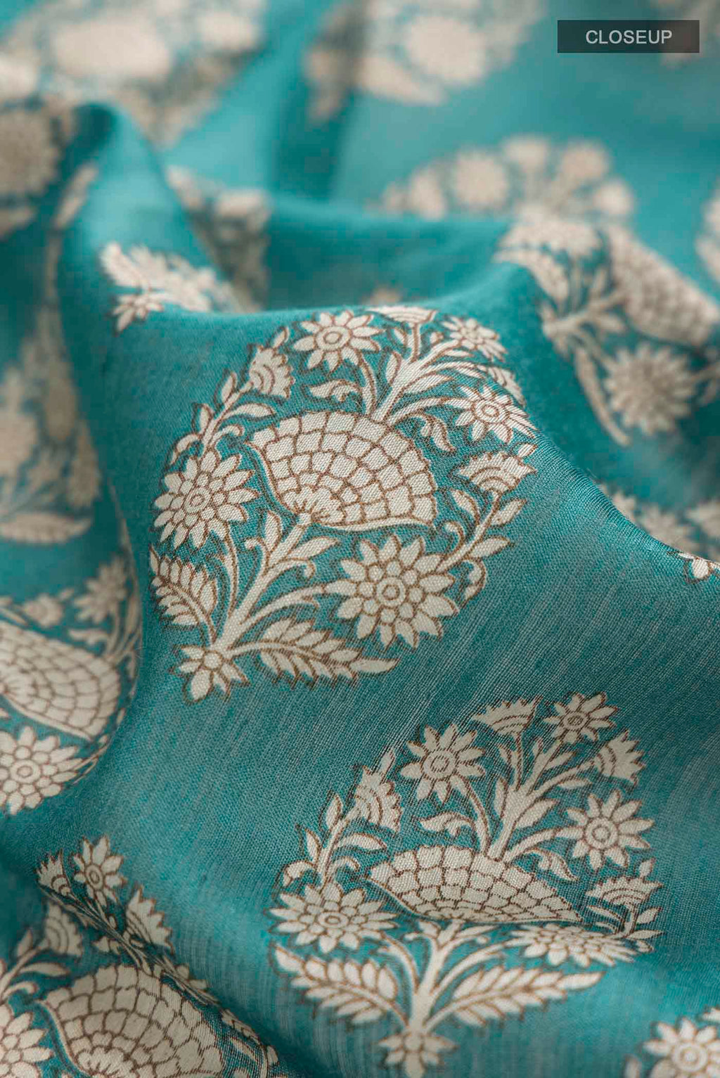 Close up of Green Tussar Silk Saree with Printed design on the body and Zari Border displaying folds