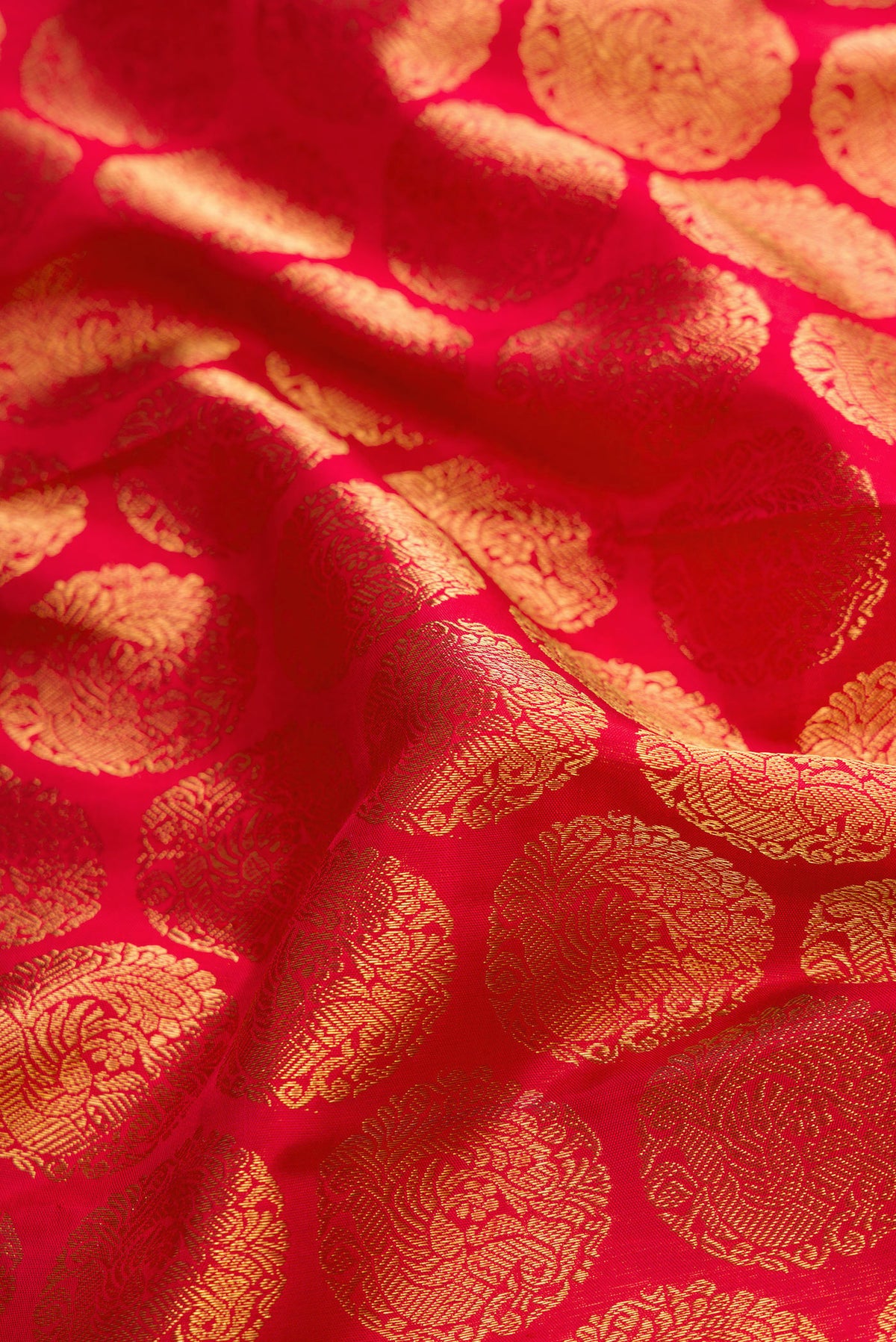 Close up of Pure Silk Pure Zari Red Dual Tone Kanjivaram Saree with Zari Brocade on the body and Zari Border.  displaying folds