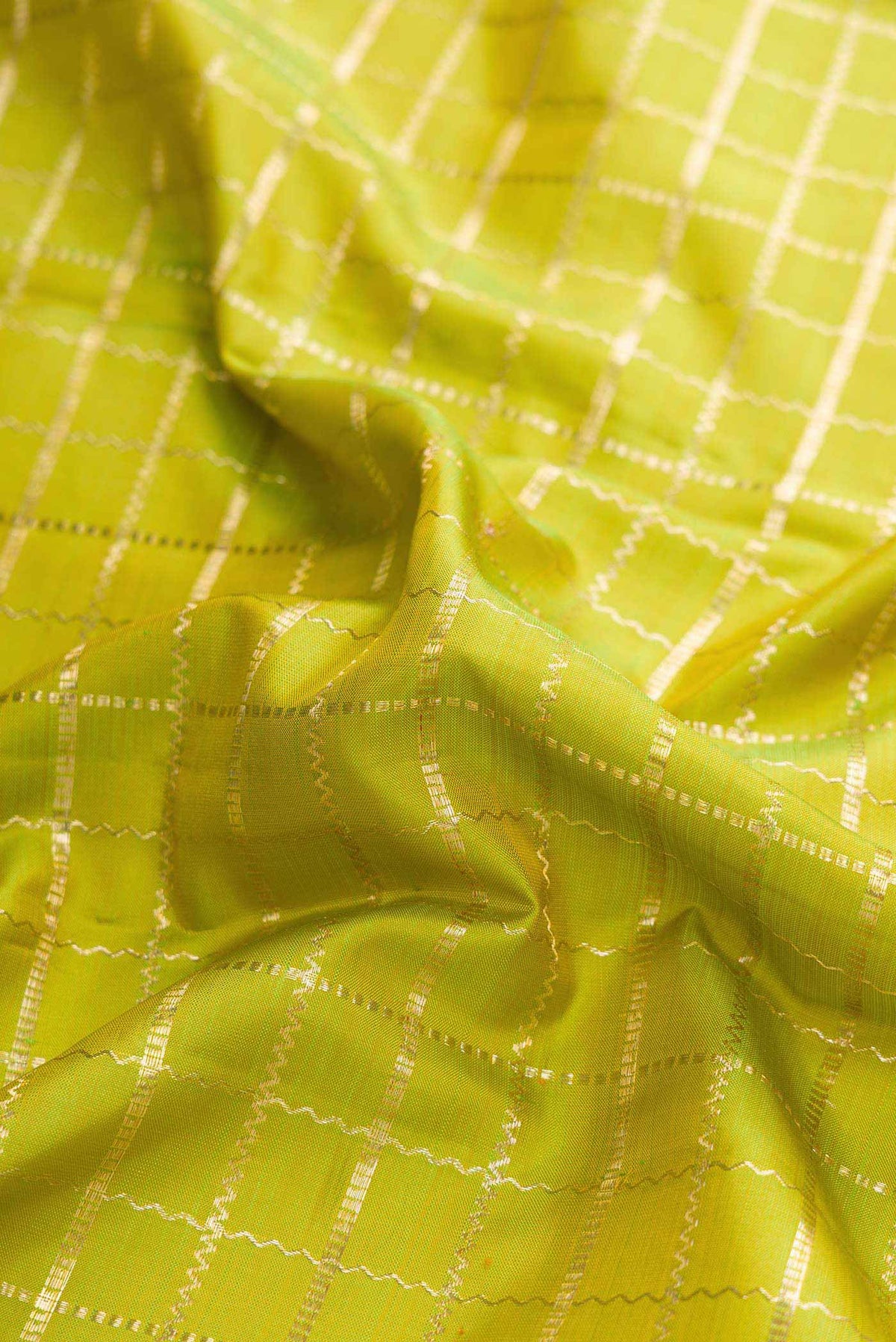 Close up of Parrot Green Kanchipuram Silk Saree with Checked design on the body and Zari Border displaying folds