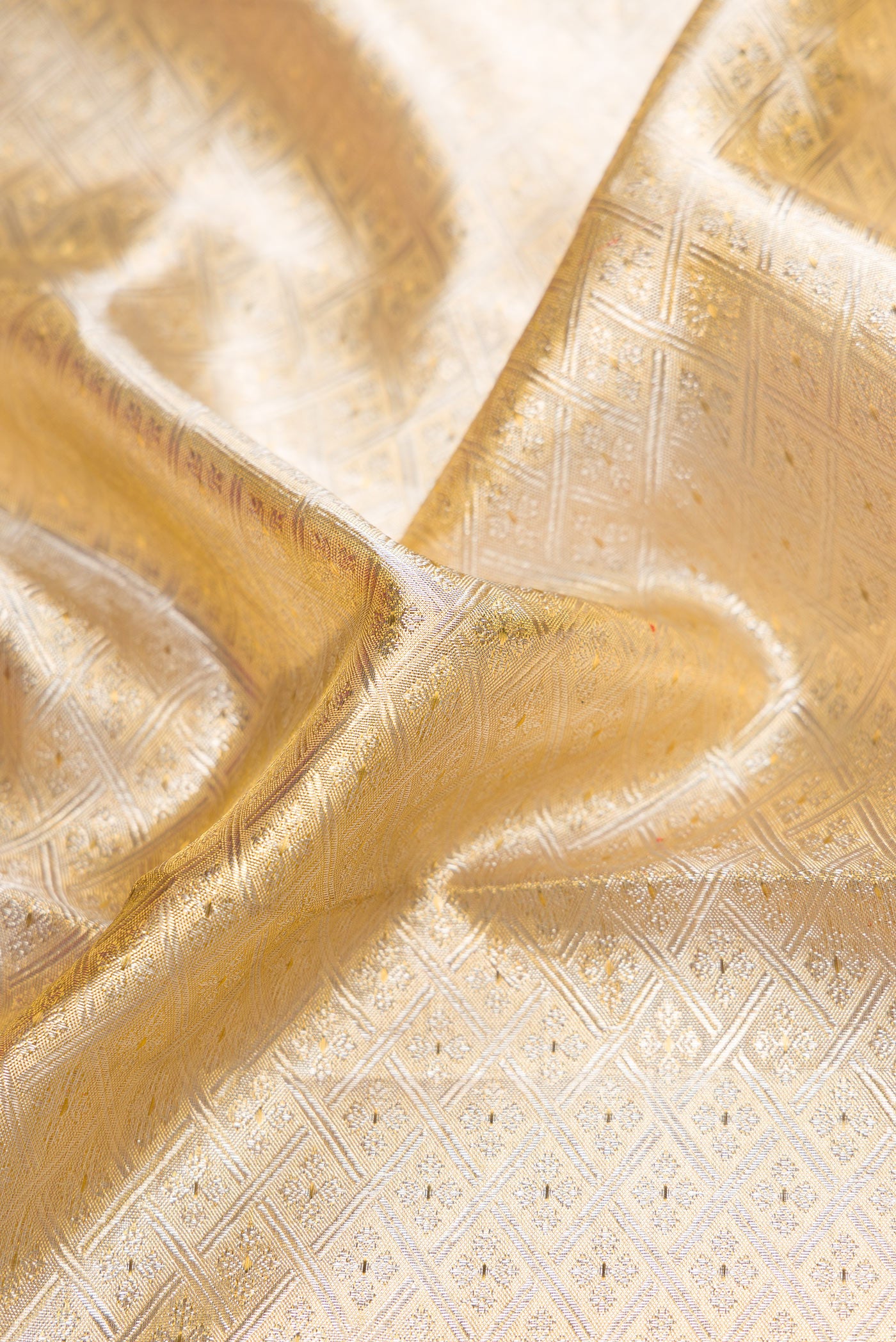 Close up of Gold Dual Tone Kanjivaram Tissue Silk Saree with Zari Brocade on the body and Zari Border.  displaying folds