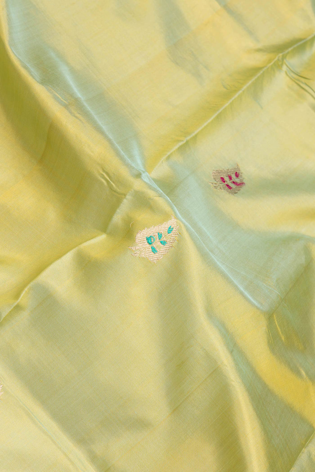 Close up of Pista Green Dual Tone Banarasi Silk Saree with Zari And Thread Butta on the body and Zari Border.  displaying folds