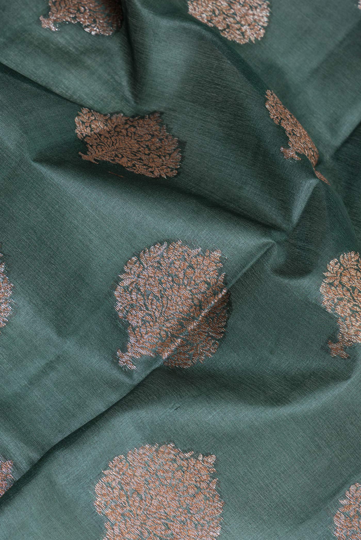 Close up of Bottle Green Banarasi Tussar Silk Saree with Zari Butta on the body and Zari Border.  displaying folds