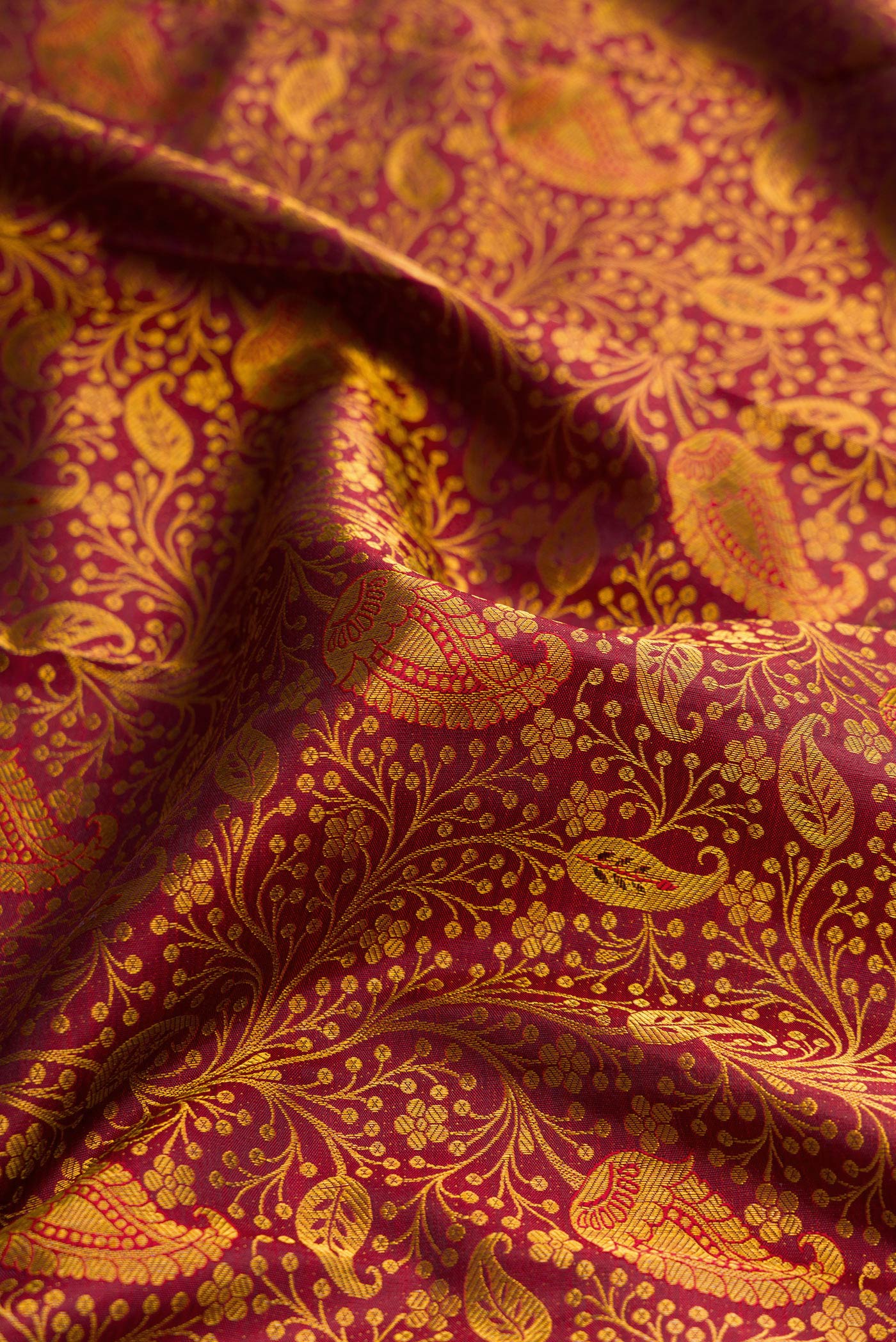 Close up of Maroon Dual Tone Kanjivaram Silk Saree with Zari Brocade on the body and Zari Border.  displaying folds