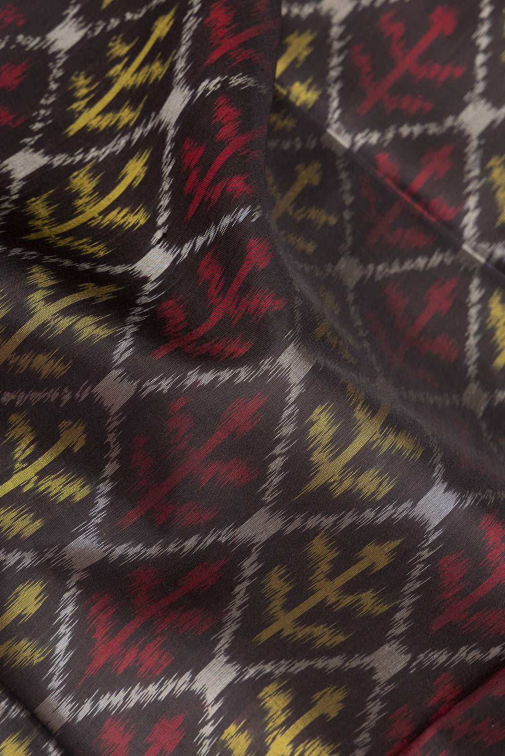 Close up of Pure Silk Black Dual Tone Soft Saree with Ikat Print on the body and Ikat Border.  displaying folds