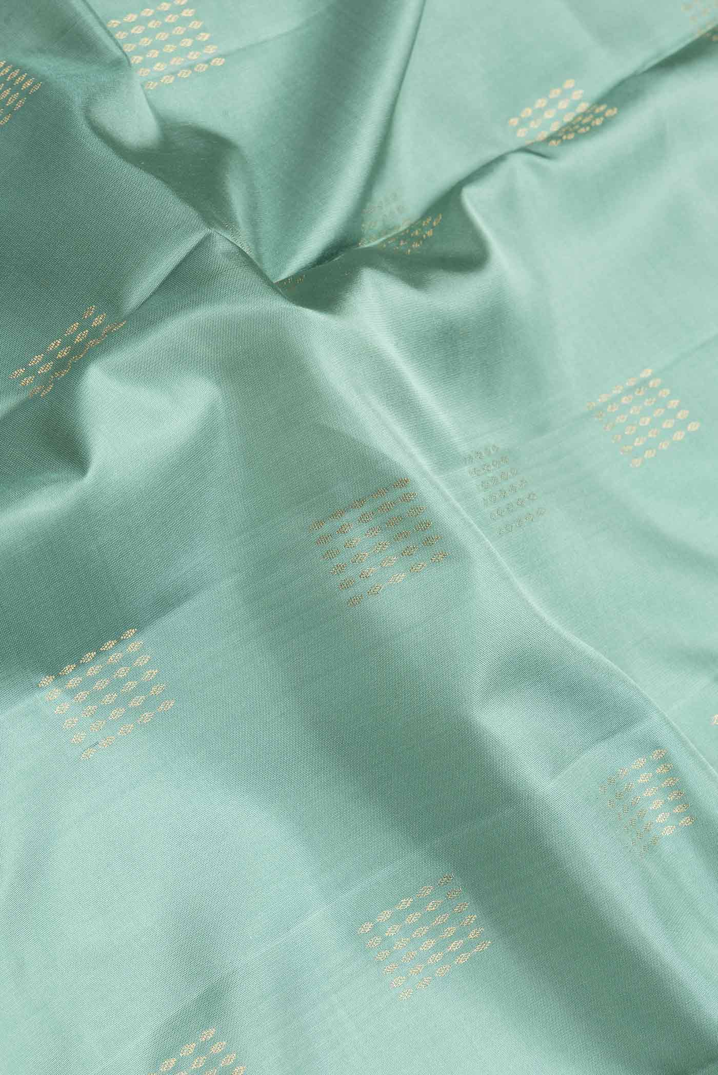 Close up of Sea Green Dual Tone Soft Silk Saree with Zari Butta on the body and Zari Border.  displaying folds