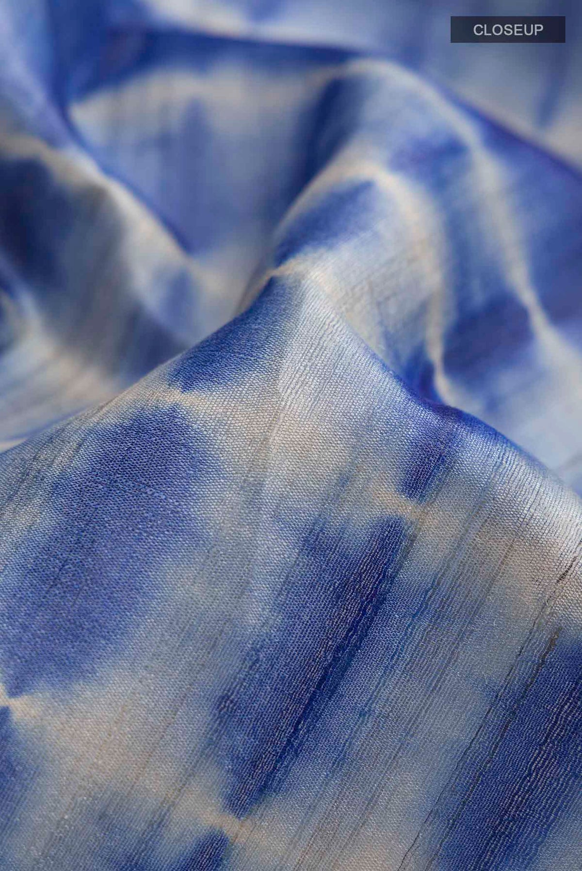 Close up of Blue Tussar Silk Saree with Printed design on the body and Zari Border displaying folds