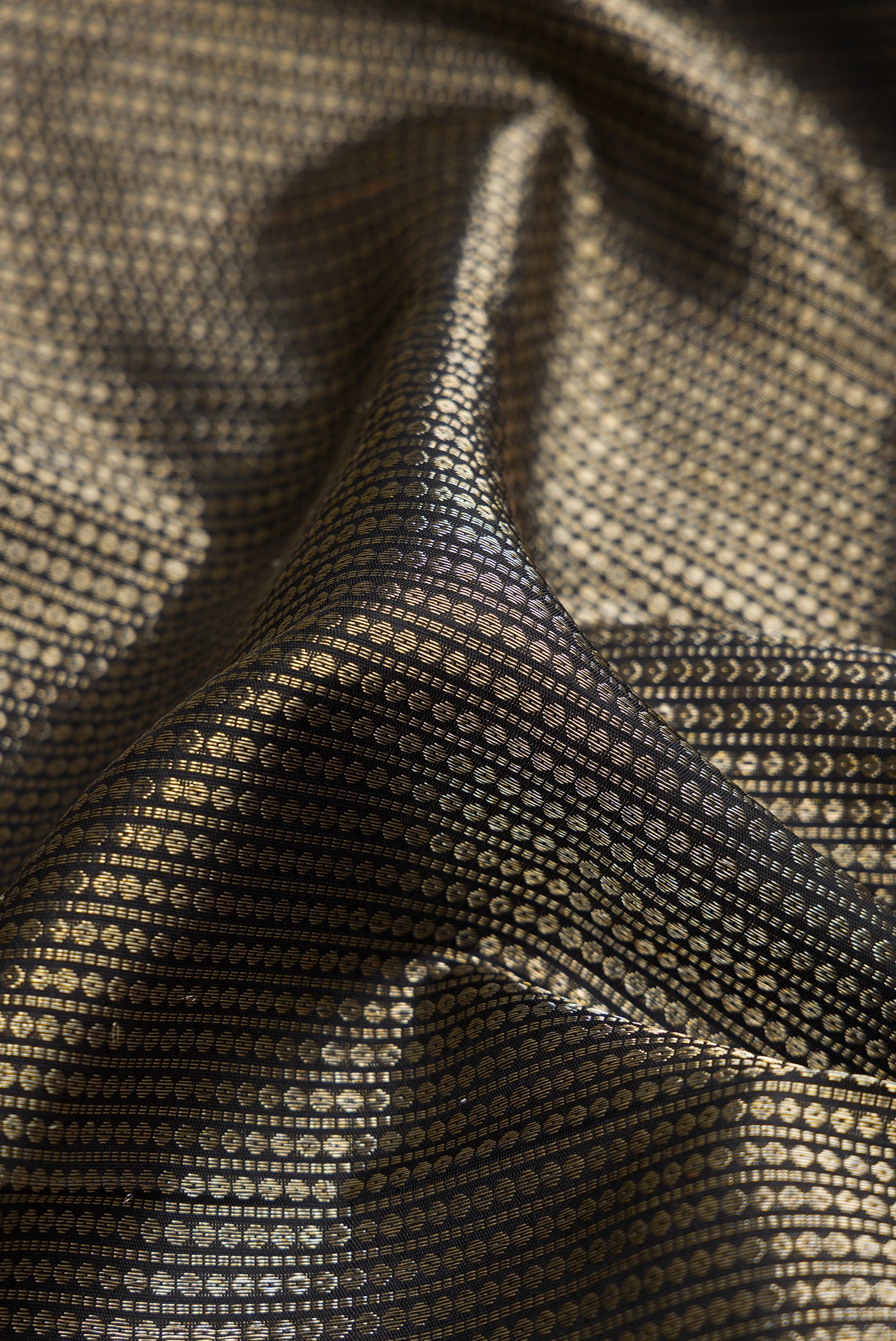 Close up of Black Kanchipuram Silk Saree with Zari Brocade on the body and Zari Border.  displaying folds
