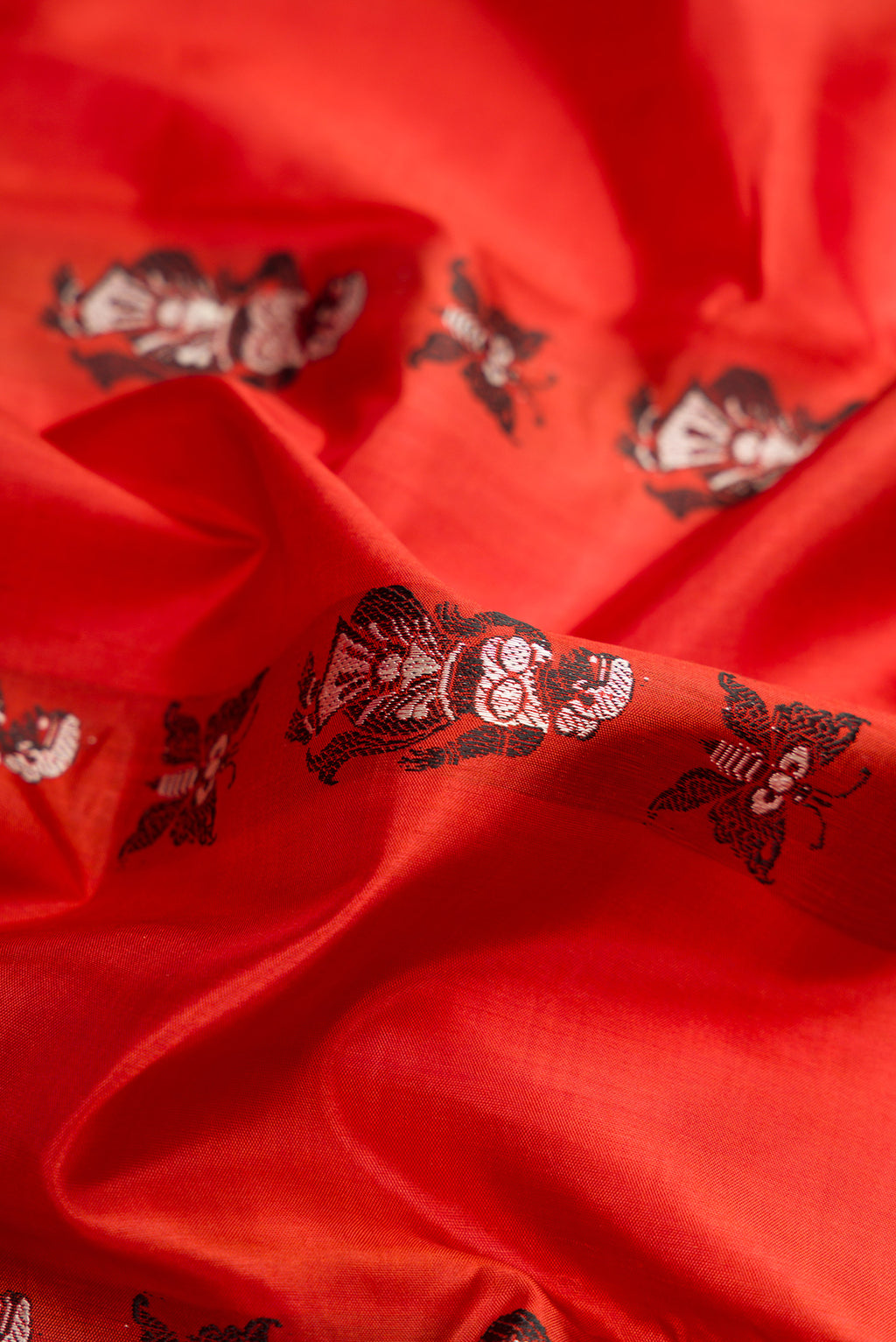 Close up of Rust Dual Tone Baluchari Silk Saree with Thread Butta on the body and Thread Border.  displaying folds