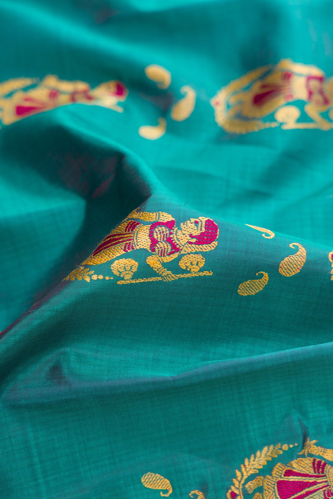 Close up of Peacock Blue Dual Tone Baluchari Silk Saree with Thread Butta on the body and Fancy Border.  displaying folds