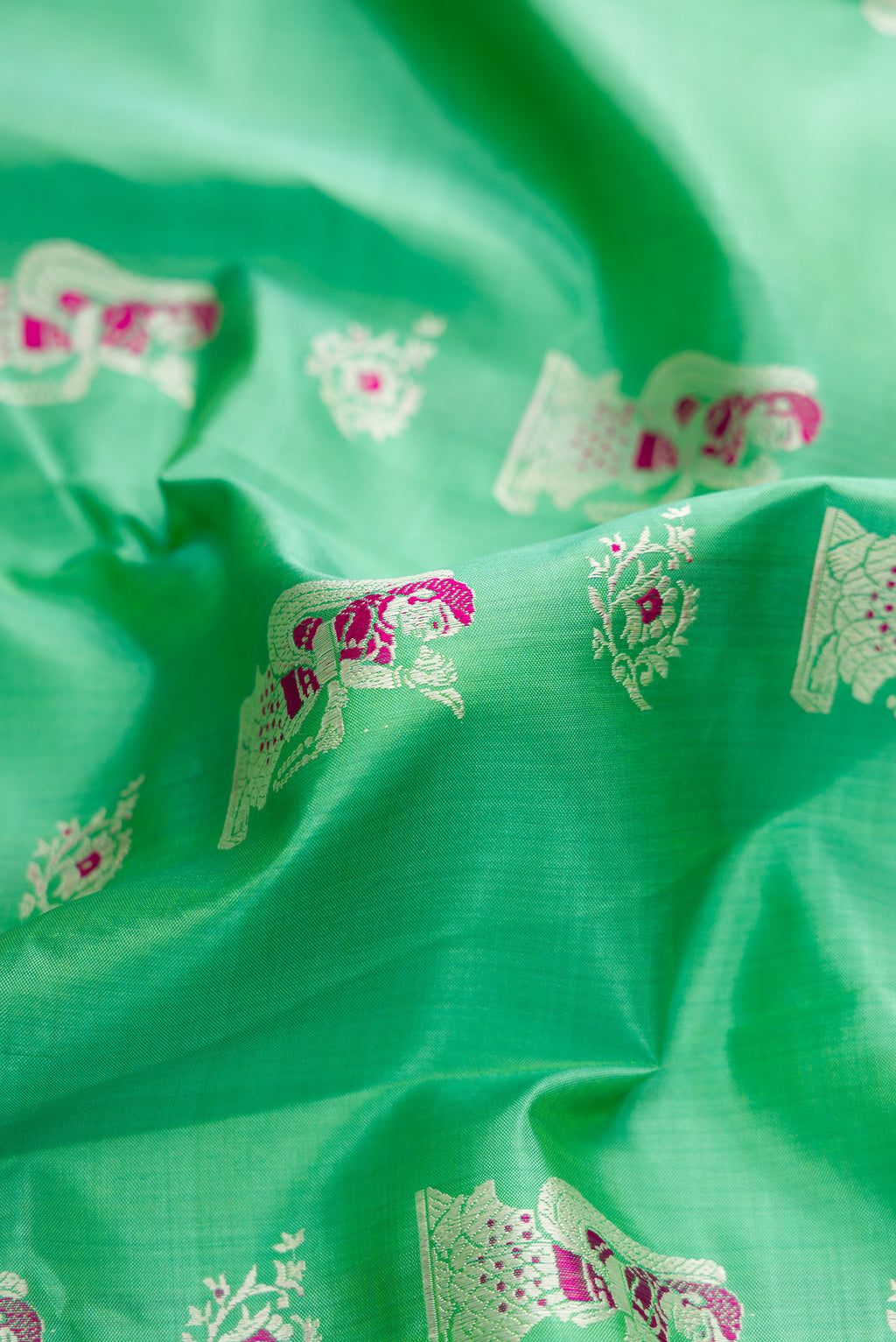 Close up of Sea Green Dual Tone Baluchari Silk Saree with Zari And Thread Butta on the body and Zari Border.  displaying folds