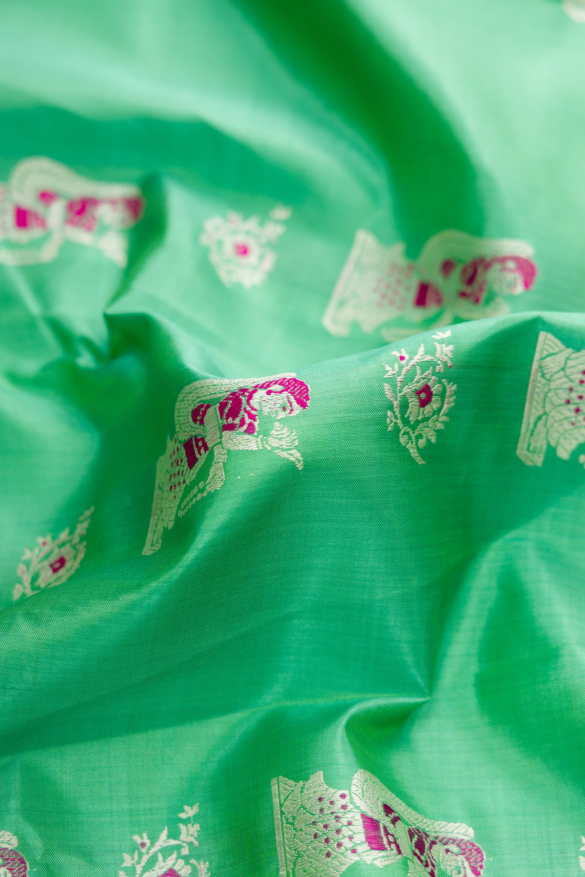 Close up of Sea Green Dual Tone Baluchari Silk Saree with Zari And Thread Butta on the body and Zari Border.  displaying folds