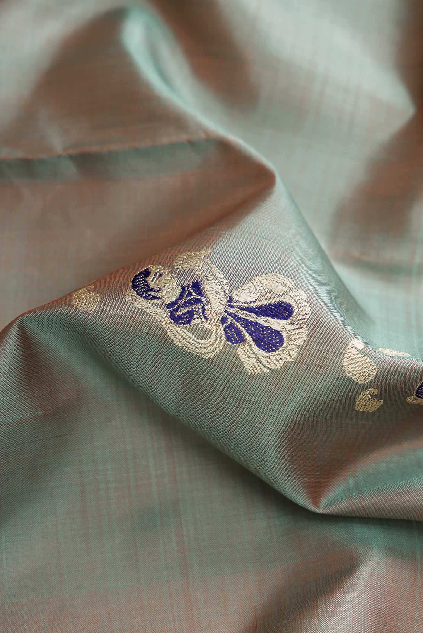 Close up of Light Blue Dual Tone Baluchari Silk Saree with Thread Butta on the body and Thread Border.  displaying folds