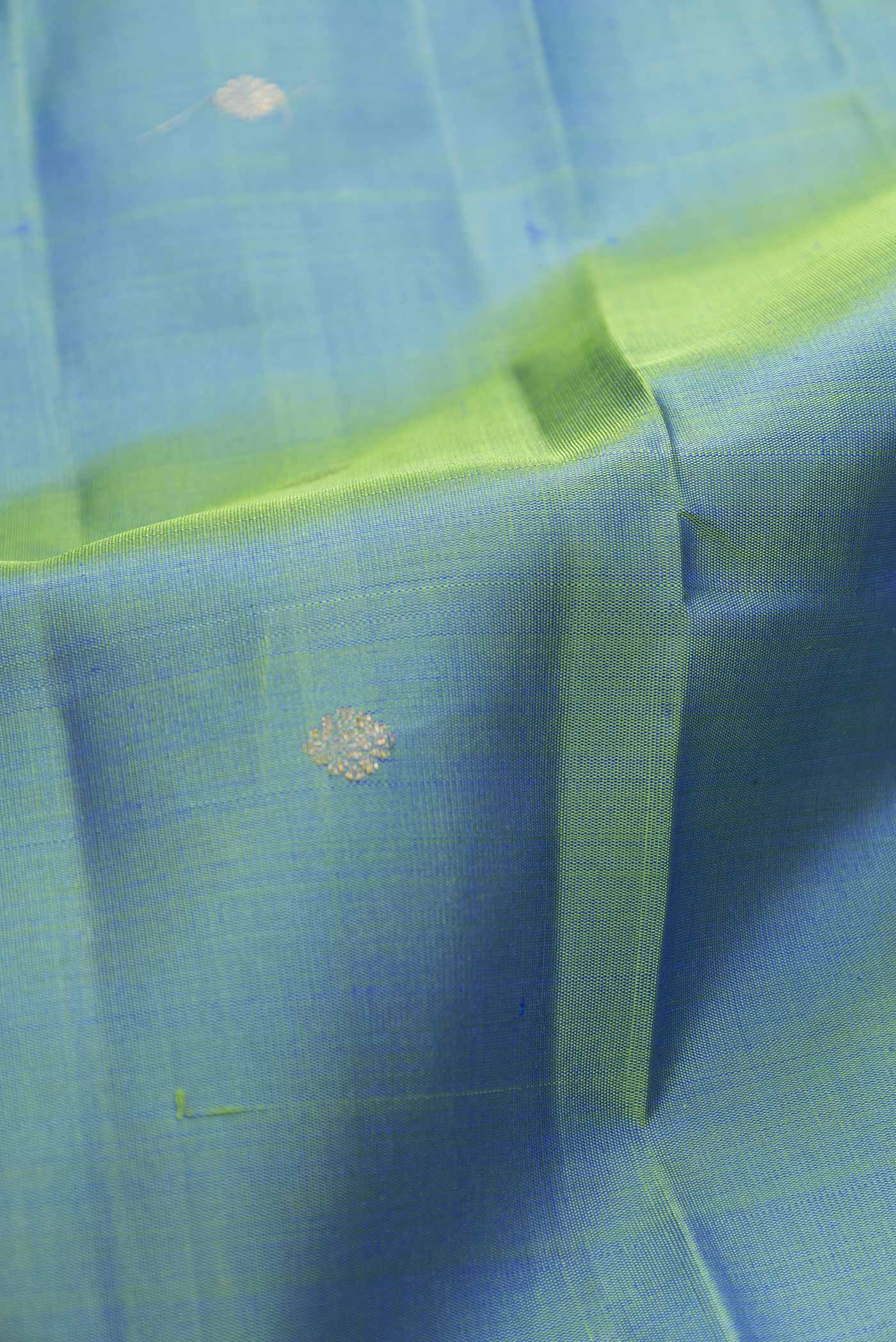 Close up of Green Dual Tone Kanchipuram Silk Saree with Zari Butta on the body and Zari Border displaying folds