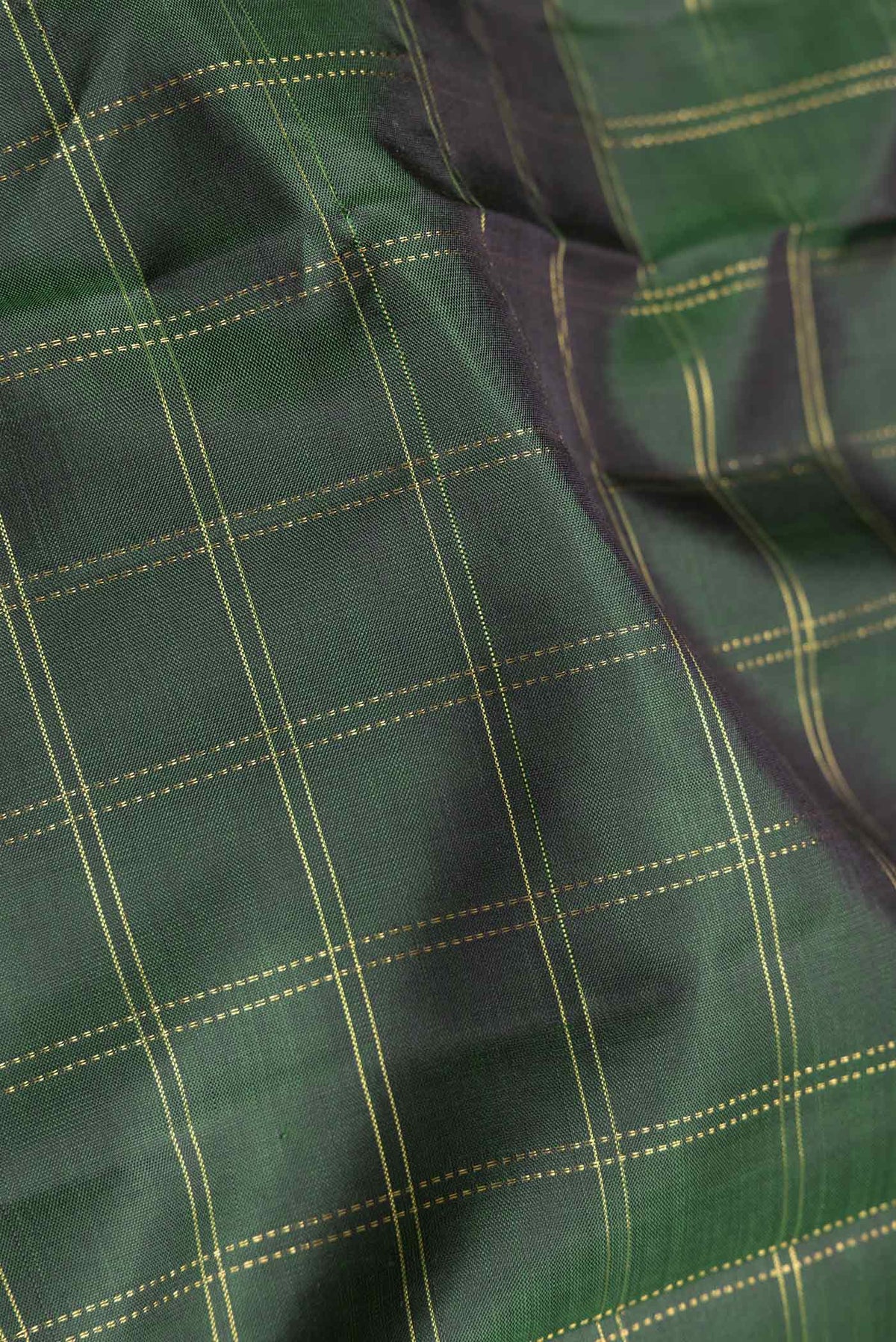 Close up of Bottle Green Dual Tone Kanchipuram Saree with Checked design on the body and Zari Border.  displaying folds