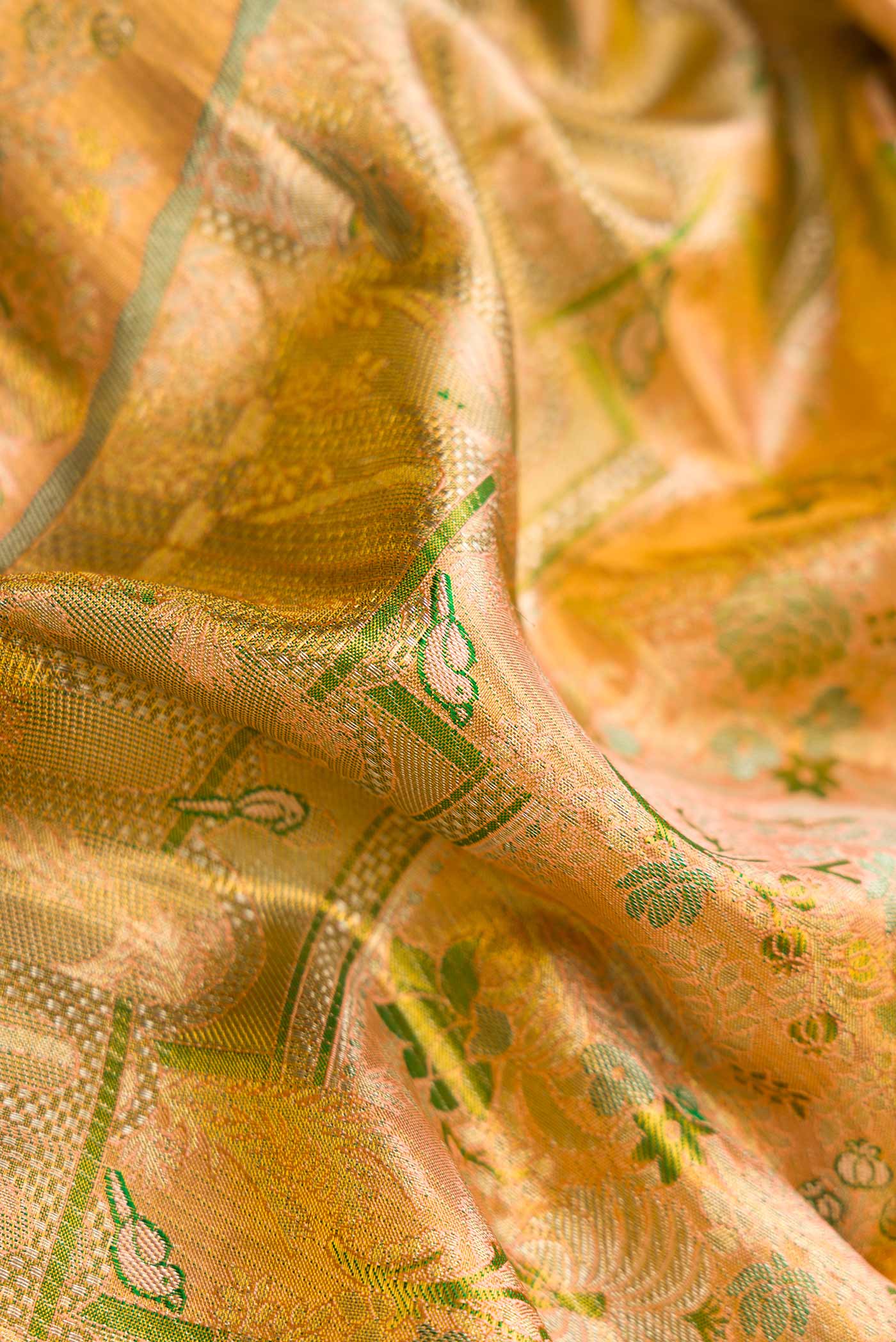 Close up of Peach Dual Tone Kanchipuram Tissue Silk Saree with Zari Brocade on the body and Zari Border.  displaying folds
