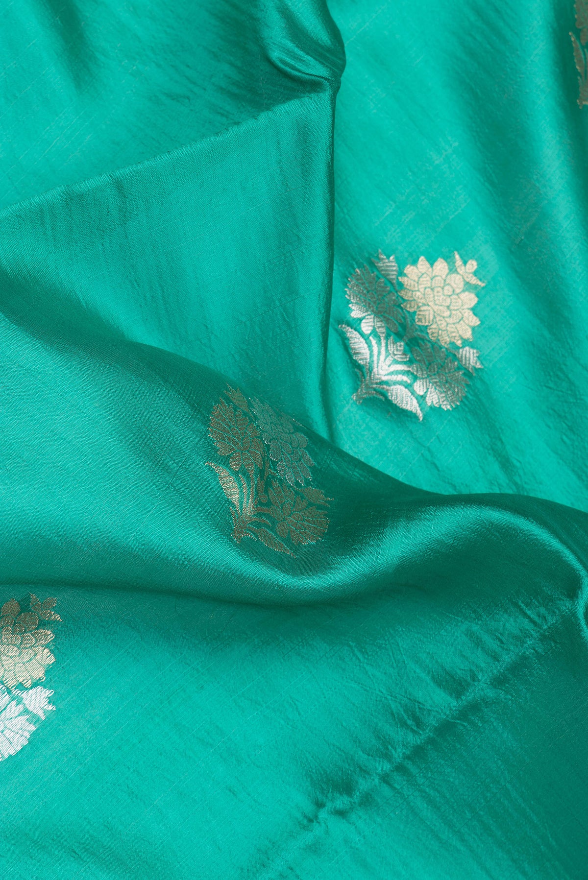 Close up of Green Dual Tone Banarasi Raw Silk Saree with Zari Butta on the body and Without Border.  displaying folds