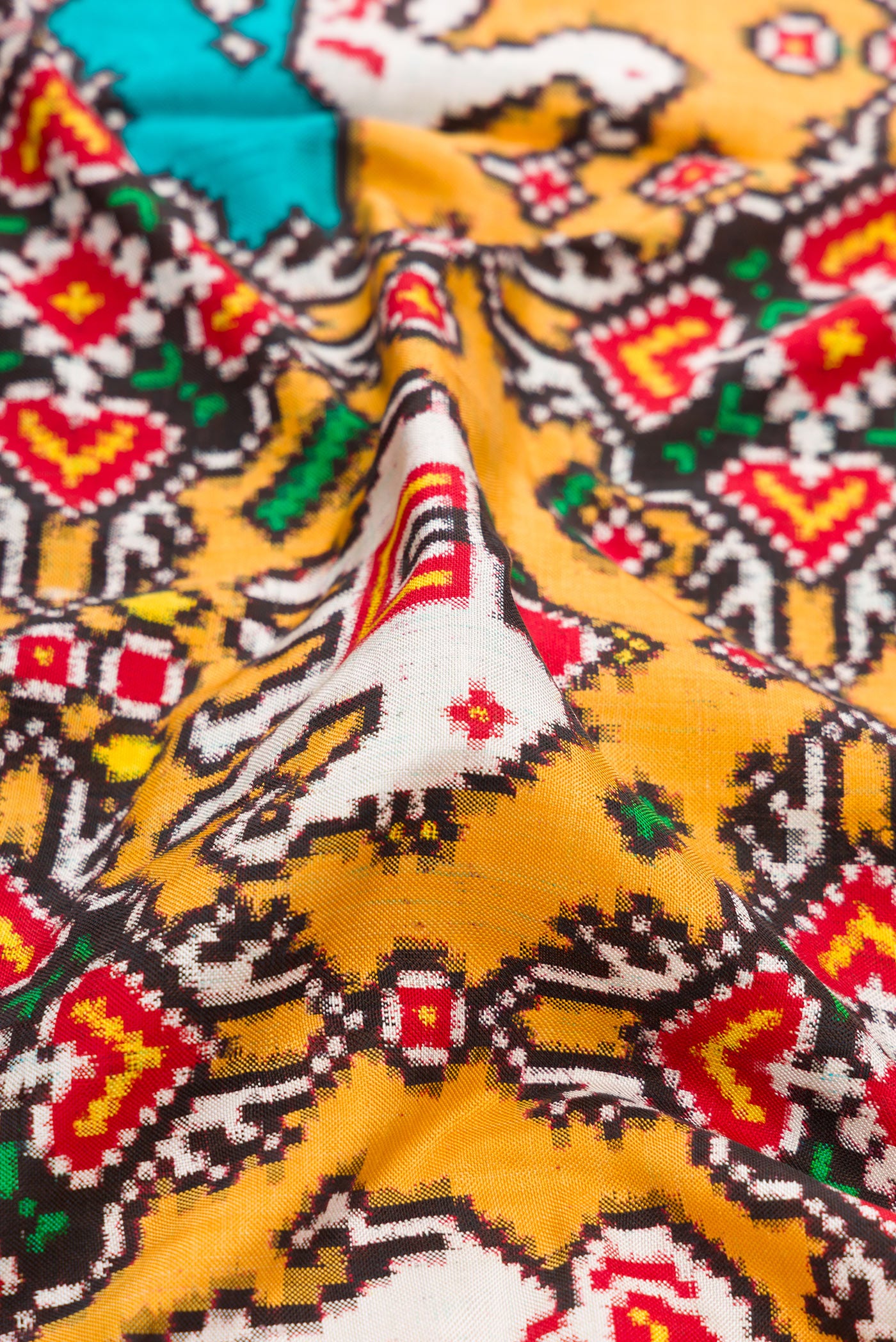Close up of Mustard Dual Tone Double Ikat Saree with Ikat Print on the body and Ikat Border.  displaying folds
