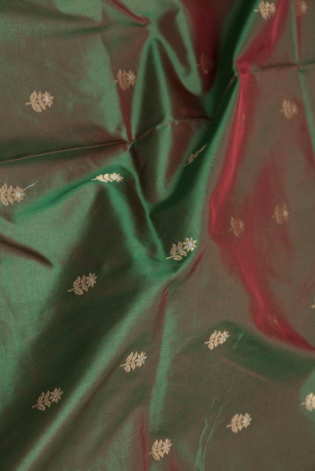 Close up of Green Dual Tone Banarasi Silk Saree with Zari Butta on the body and Plain Border displaying folds