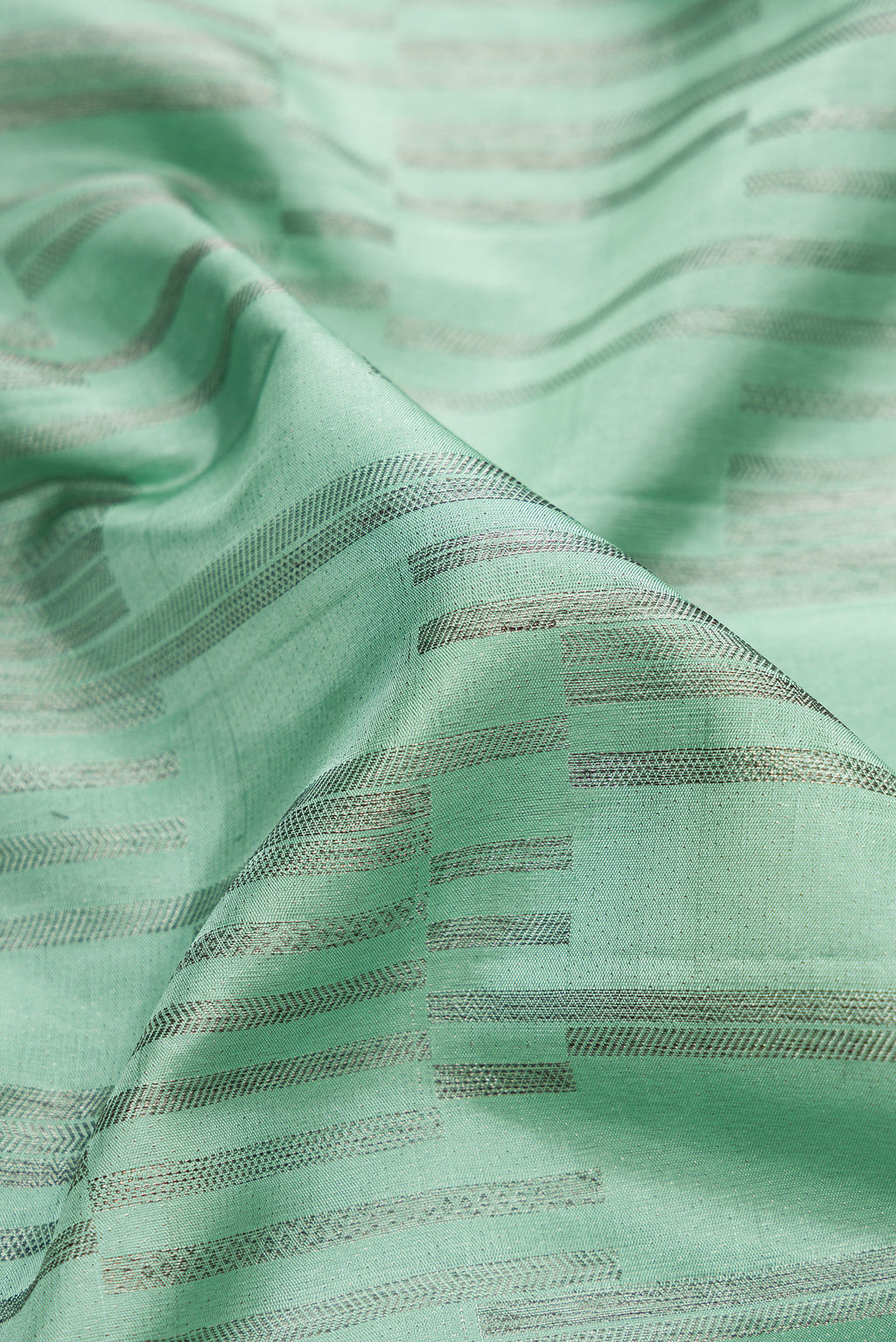 Close up of Light Green Dual Tone Kanjivaram Silk Saree with Zari Brocade on the body and Zari Border.  displaying folds