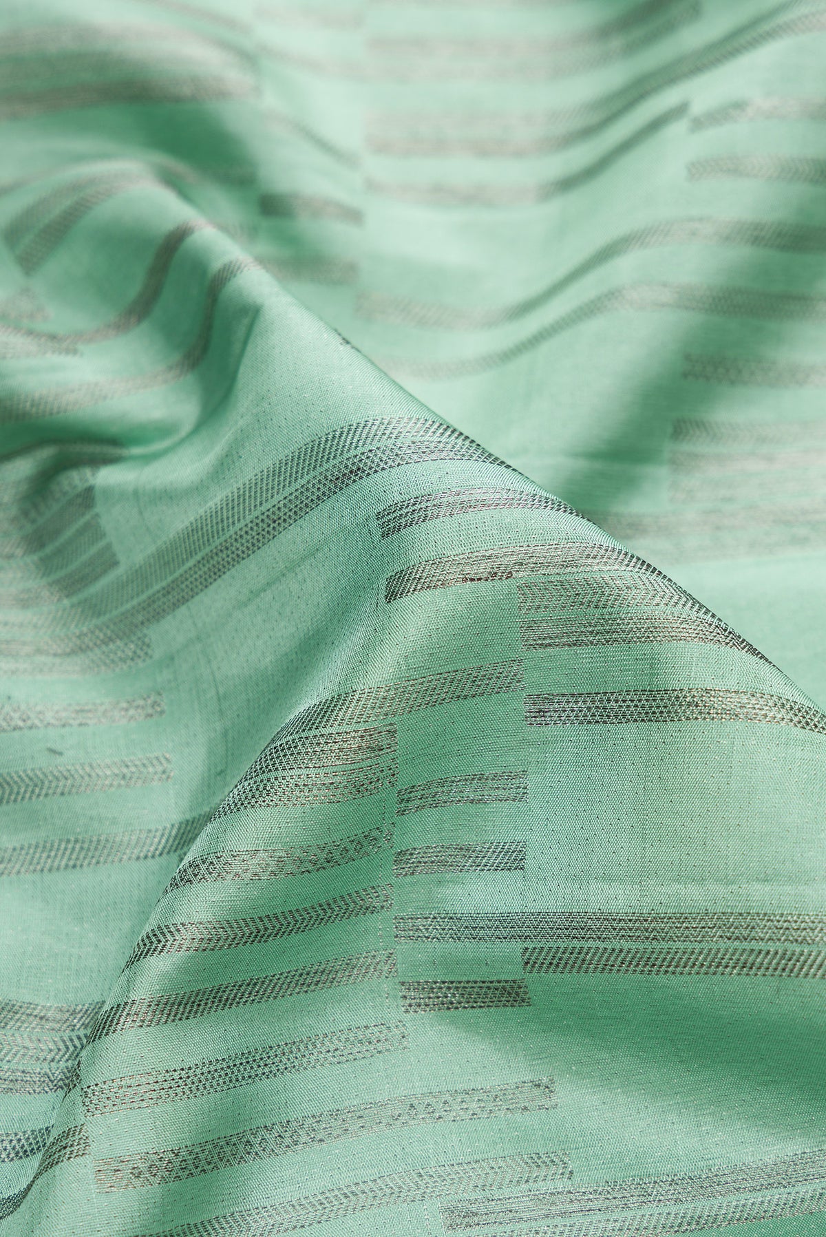 Close up of Light Green Dual Tone Kanjivaram Silk Saree with Zari Brocade on the body and Zari Border.  displaying folds