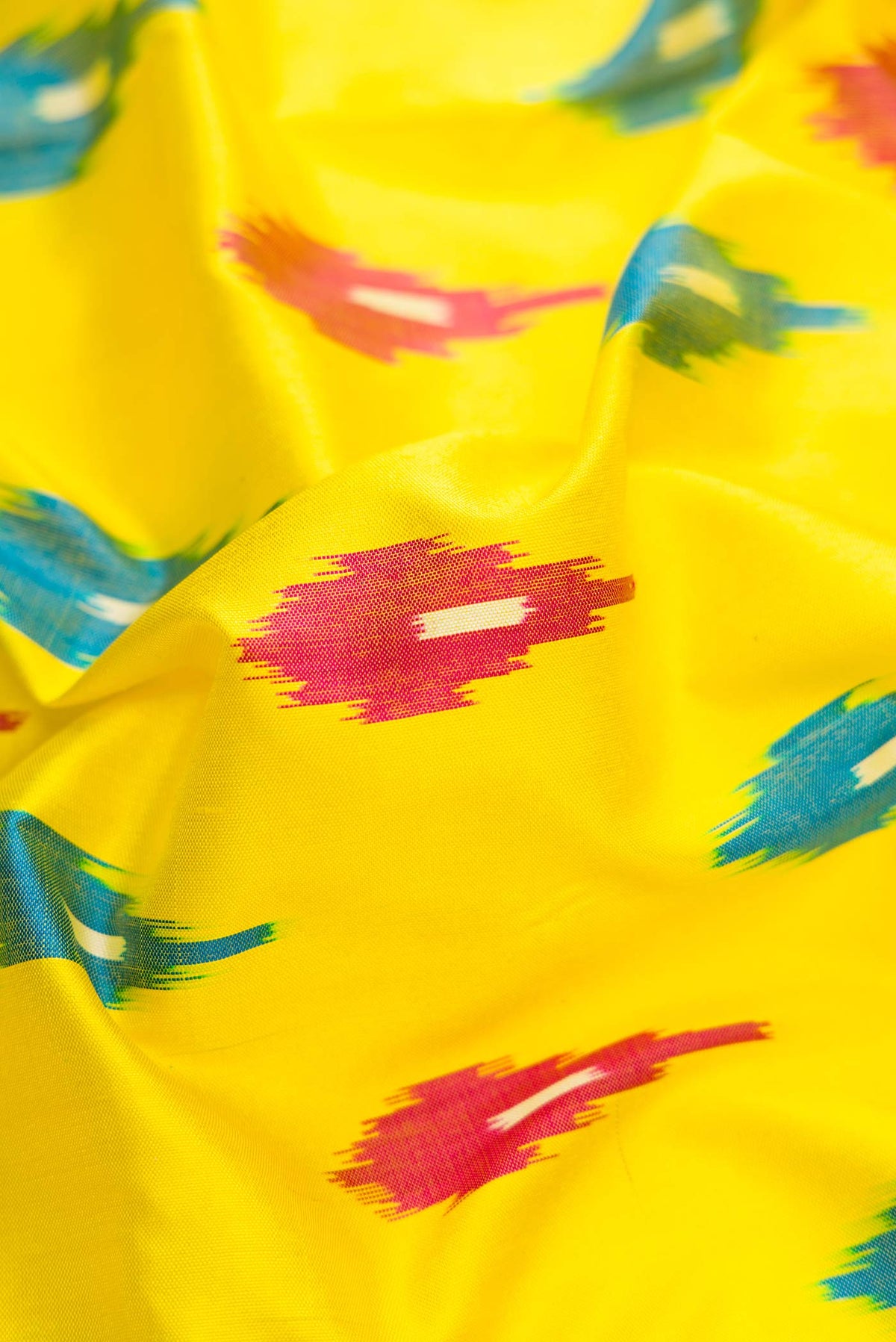 Close up of Lemon Yellow Dual Tone Double Ikat Saree with Ikat Print on the body and Ikat Border.  displaying folds