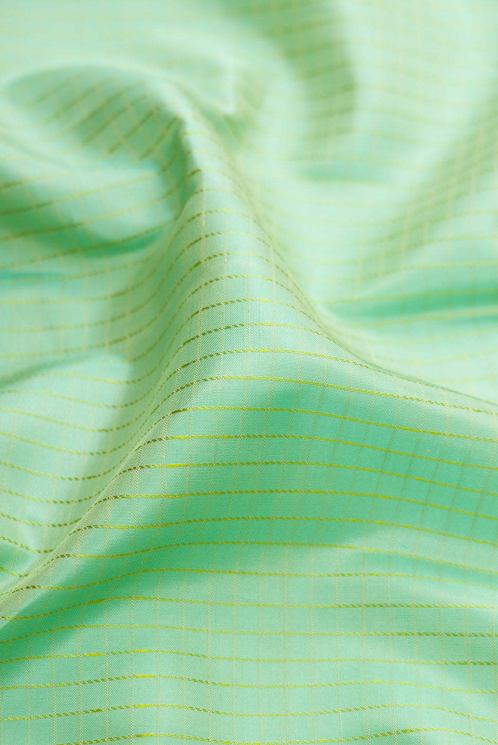 Close up of Mint Green Kanchipuram Silk Saree with Checked design on the body and Thread Border.  displaying folds