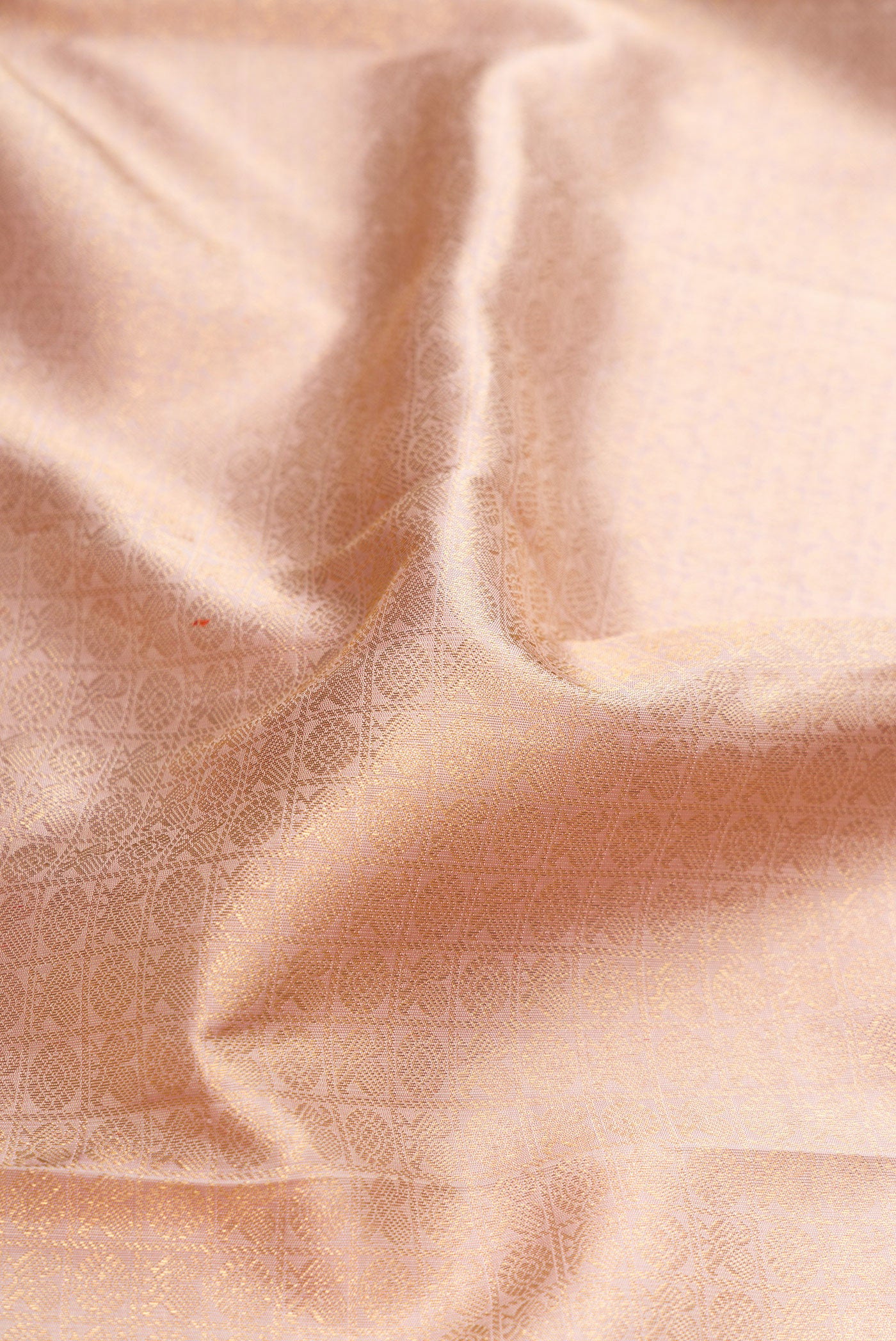 Close up of Pure Silk Pure Zari Rose Gold Dual Tone Kanjivaram Saree with Zari Brocade on the body and Zari Border.  displaying folds