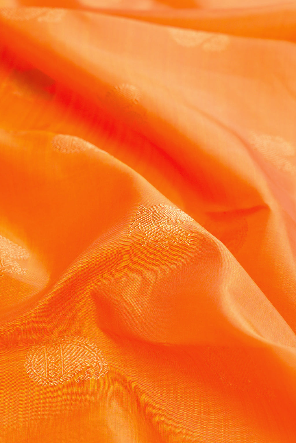 Close up of Pure Silk Pure Zari Orange Dual Tone Kanchipuram Saree with Zari Butta on the body and Zari Border.  displaying folds