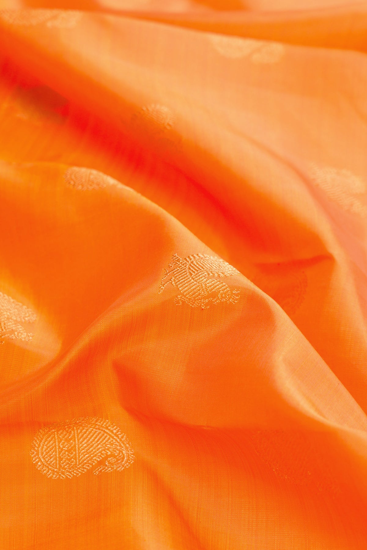 Close up of Pure Silk Pure Zari Orange Dual Tone Kanchipuram Saree with Zari Butta on the body and Zari Border.  displaying folds