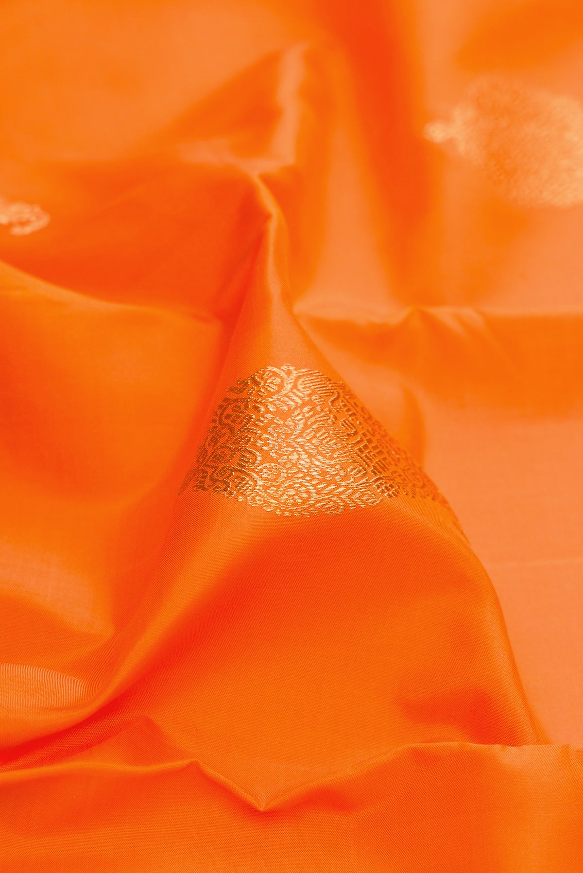 Close up of Pure Silk Pure Zari Orange Kanjivaram Saree with Zari Butta on the body and Zari Border.  displaying folds