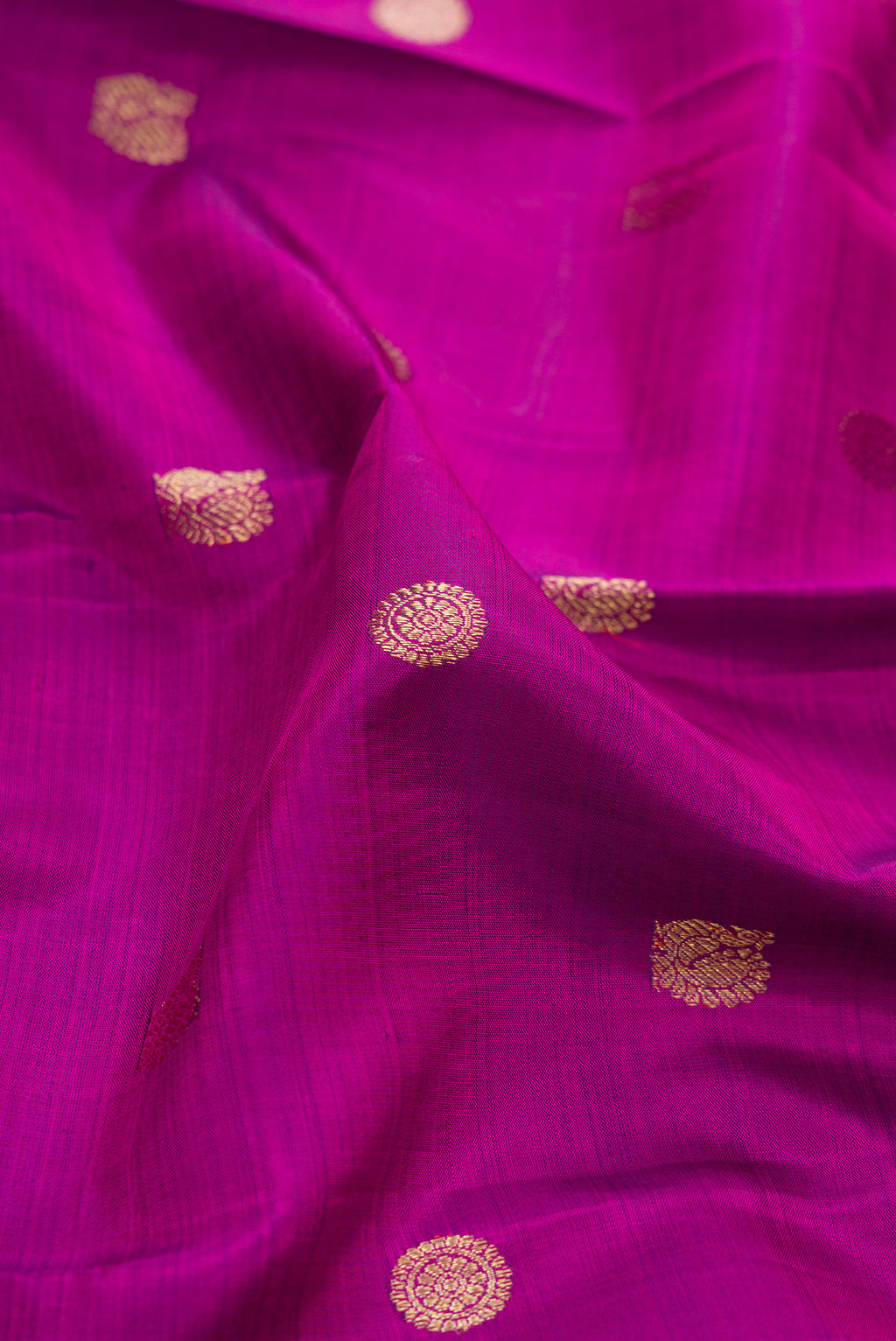 Close up of Pure Silk Pure Zari Magenta Dual Tone Kanchipuram Saree with Zari Butta on the body and Zari Border.  displaying folds