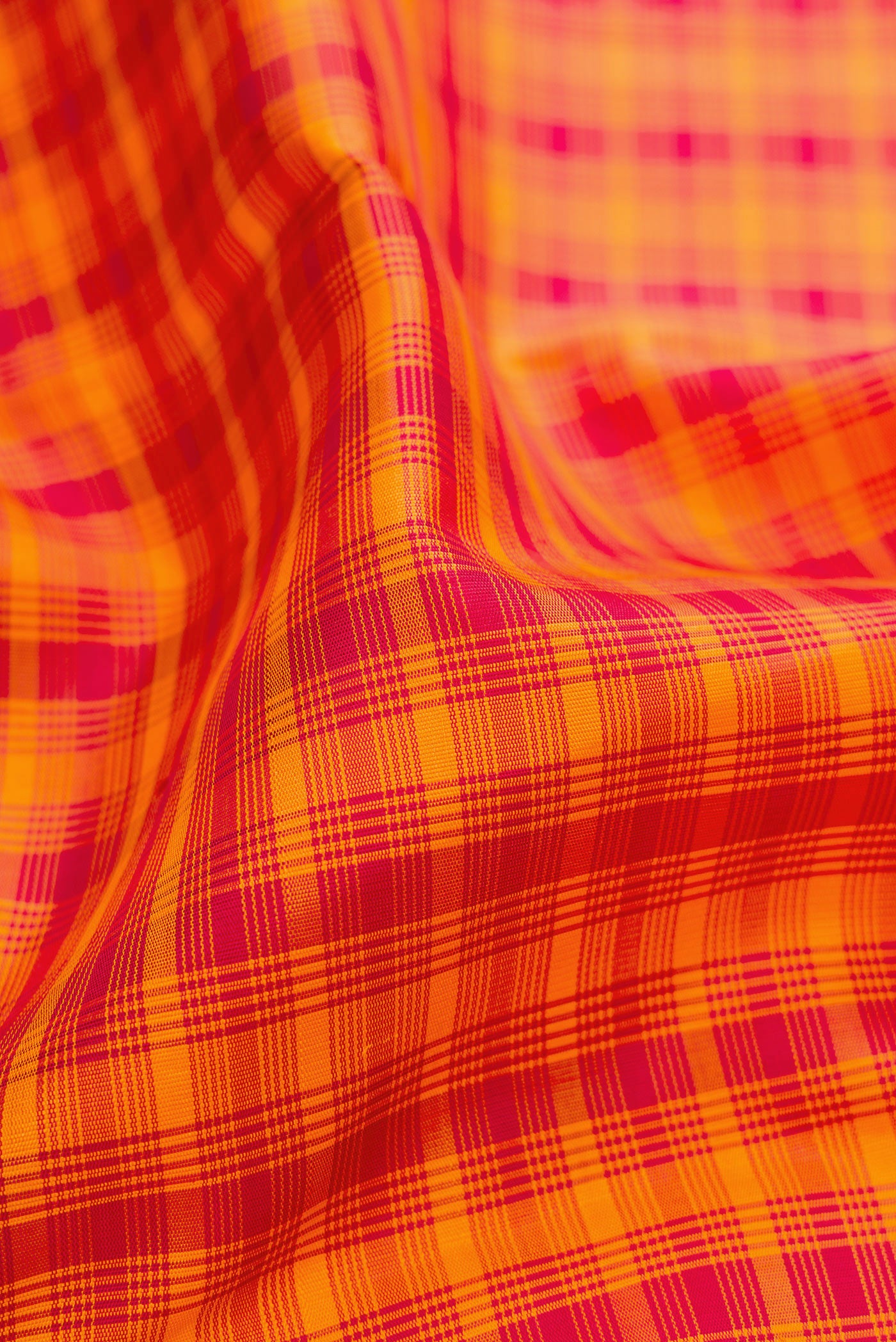 Close up of Orange Kanchipuram Silk Saree with Checked design on the body and Thread Border.  displaying folds
