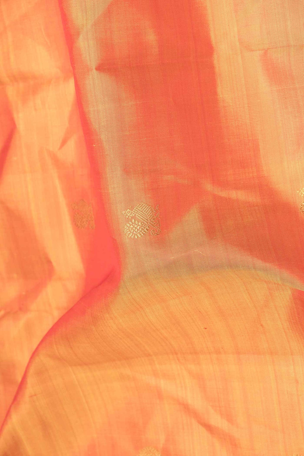 Close up of Pure Silk Pure Zari Orange Dual Tone Kanchipuram Saree with Zari Butta on the body and Zari Border displaying folds
