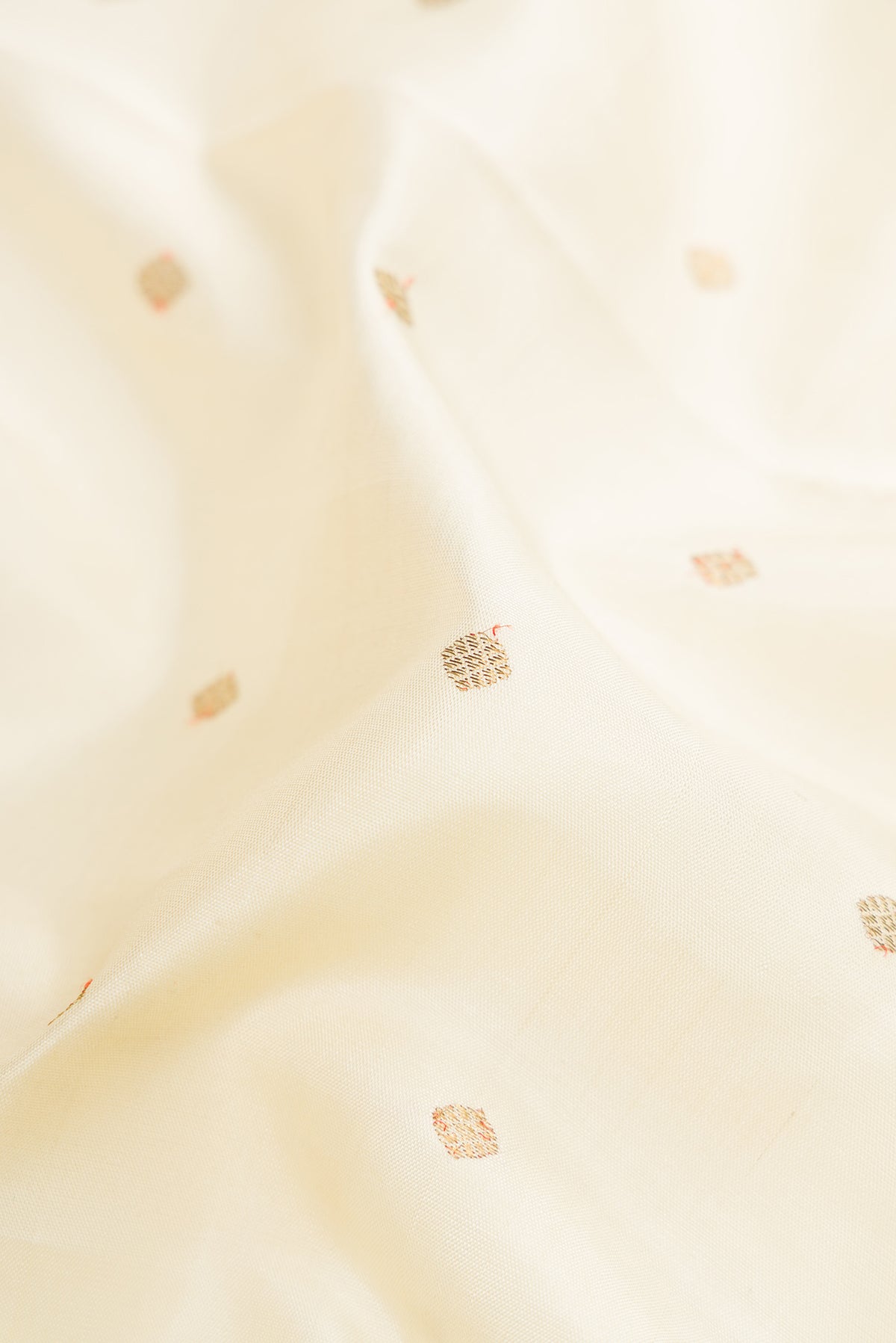 Close up of Pure Silk Pure Zari Off White Dual Tone Kanjivaram Saree with Zari Butta on the body and Zari Border.  displaying folds