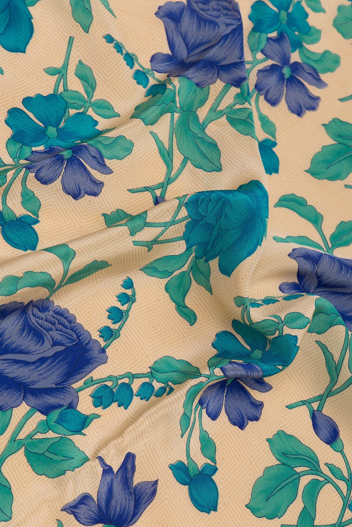 Close up of Beige Crepe Saree with Floral Print on the body and Printed Border.  displaying folds