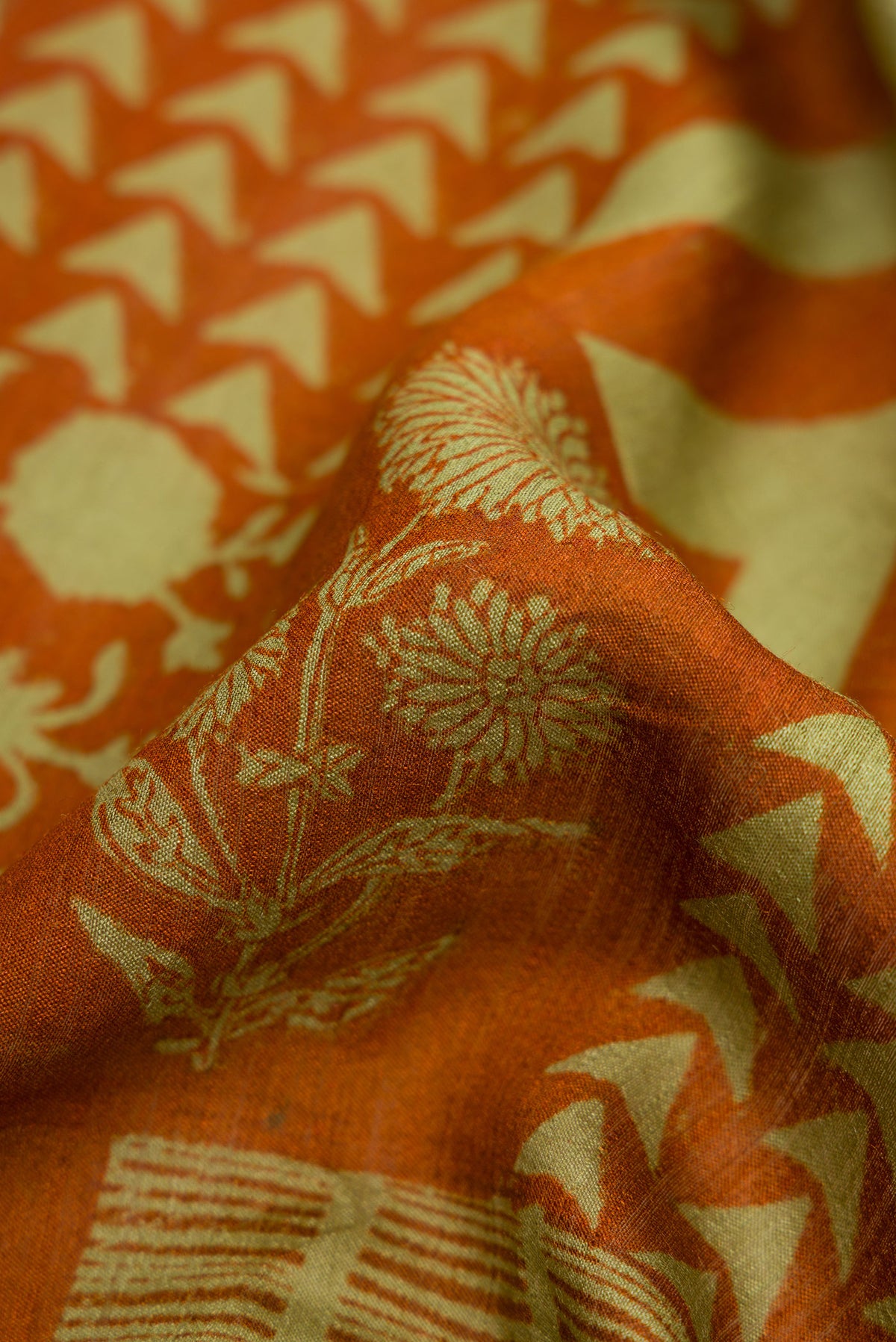 Close up of Brick Orange Dual Tone Tussar Silk Saree with Printed design on the body and Zari Border.  displaying folds