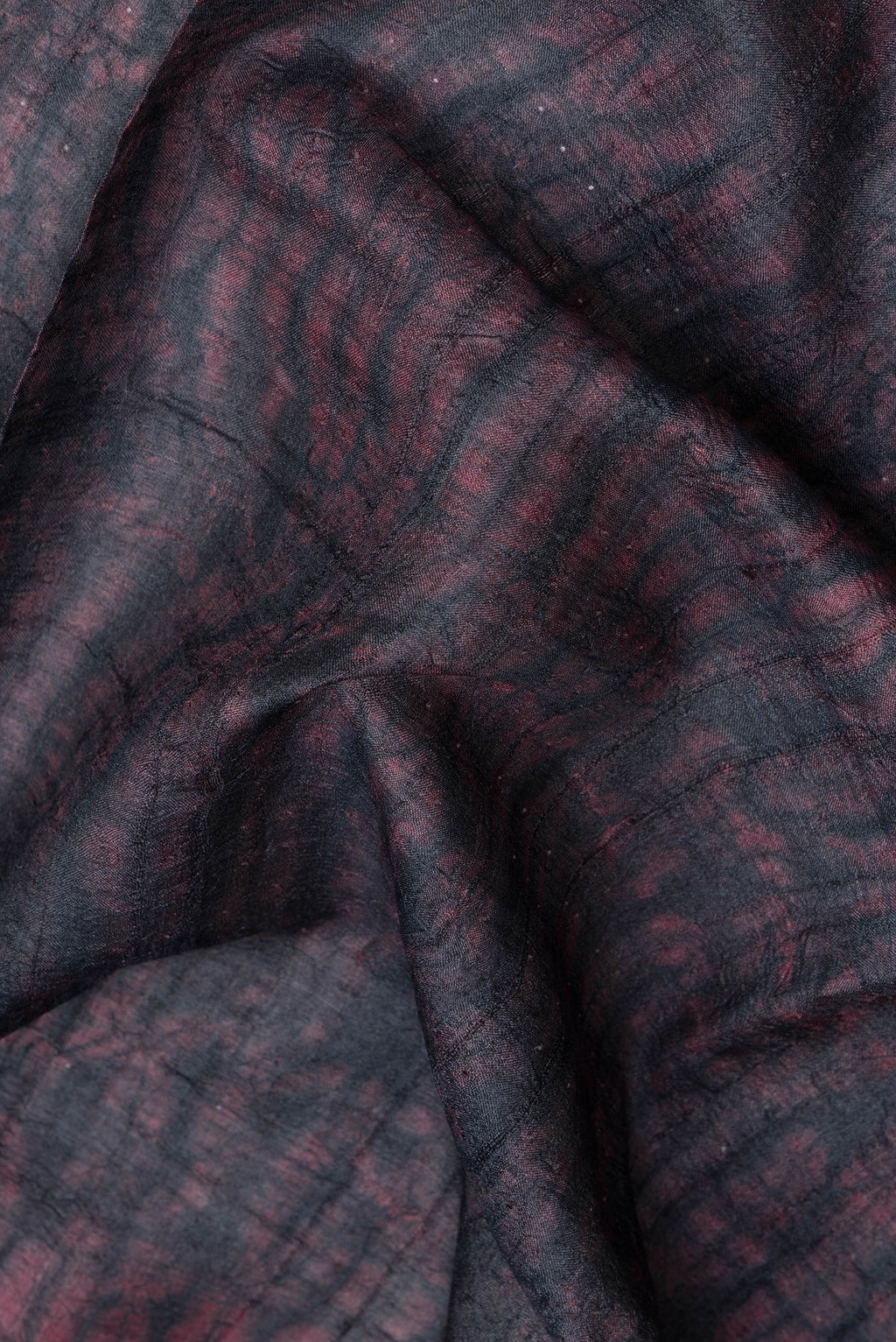 Close up of Maroon Dual Tone Tussar Silk Saree with Printed design on the body and Plain Border.  displaying folds