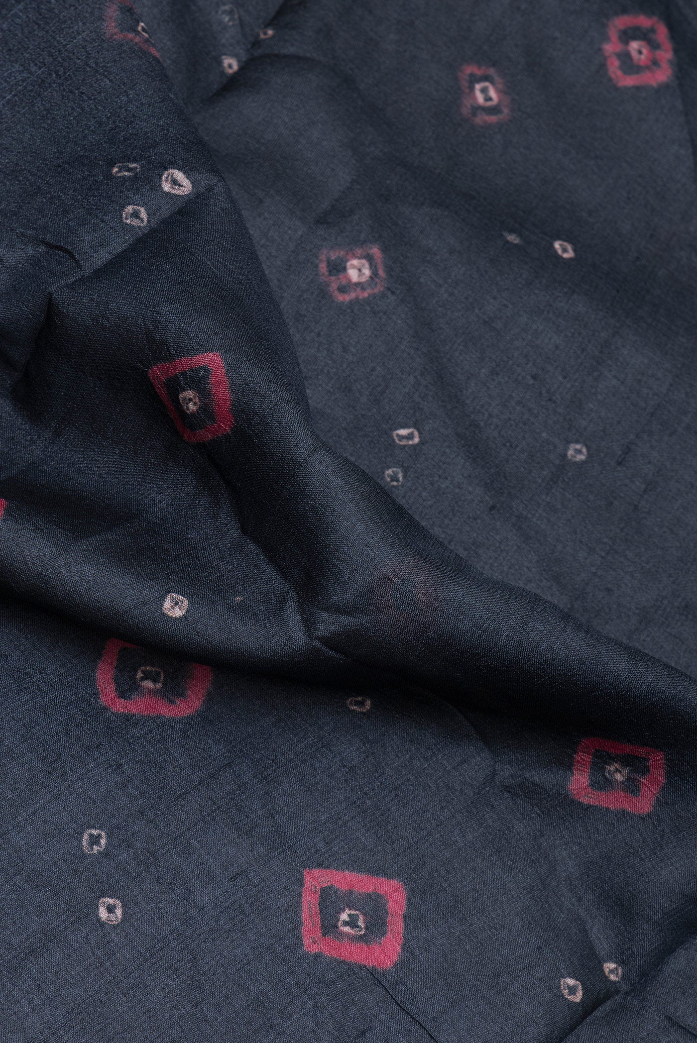 Close up of Black Tussar Silk Saree with Bandhani Print on the body and Printed Border.  displaying folds