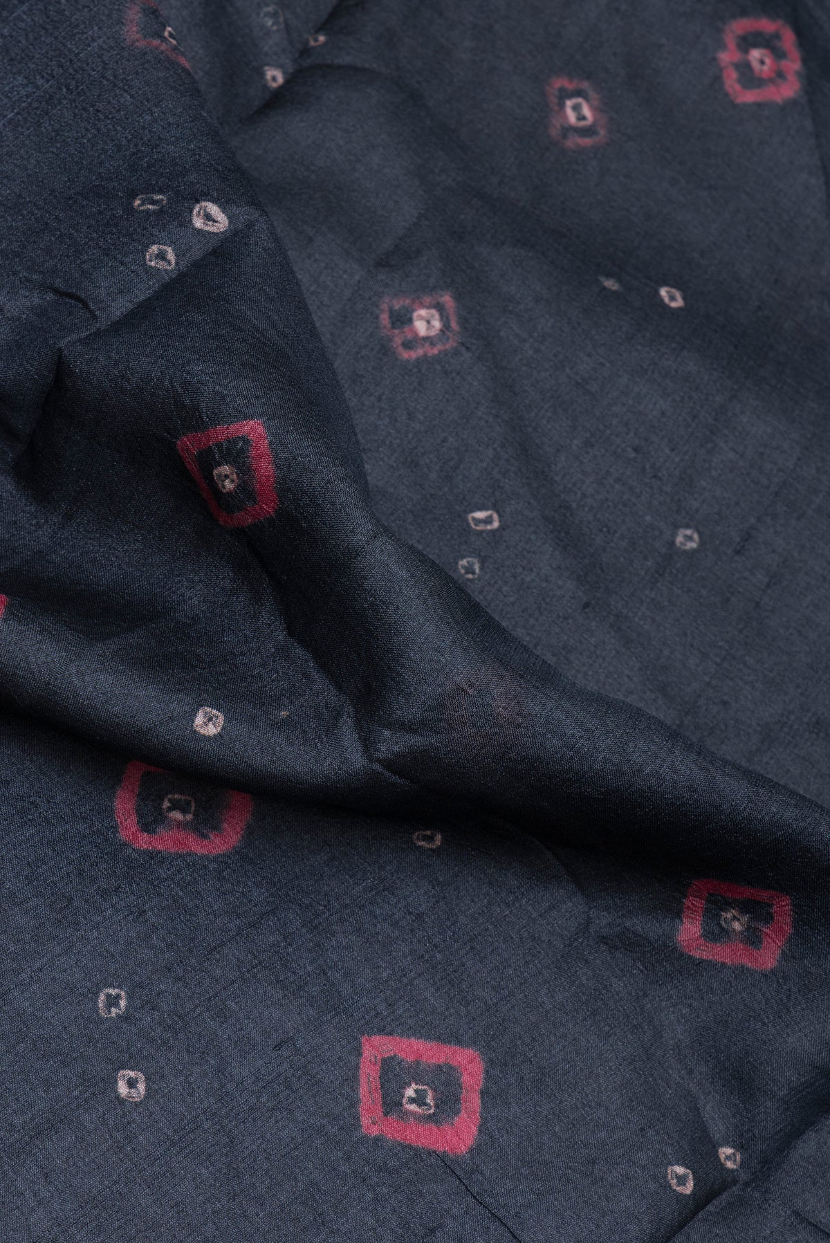 Close up of Black Tussar Silk Saree with Bandhani Print on the body and Printed Border.  displaying folds