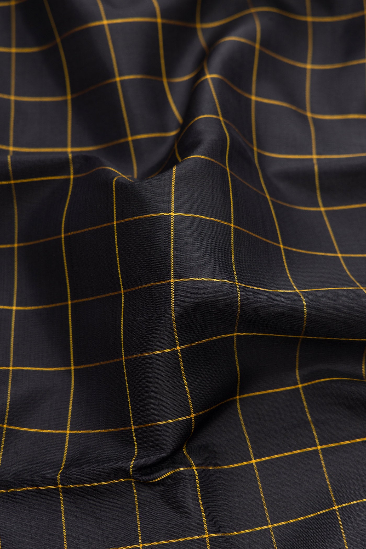 Close up of Black Dual Tone Kanchipuram Silk Saree with Checked design on the body and Temple Border.  displaying folds